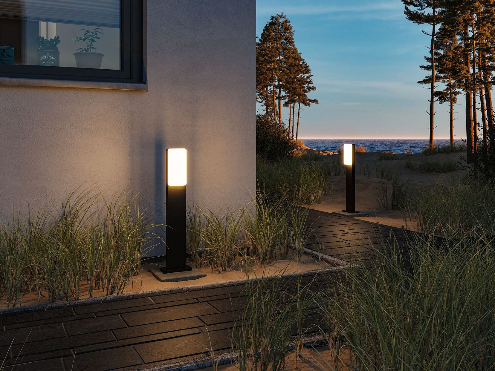 Dwie lampy zewnętrzne w pobliżu ścieżki nad brzegiem morza o zmierzchu.