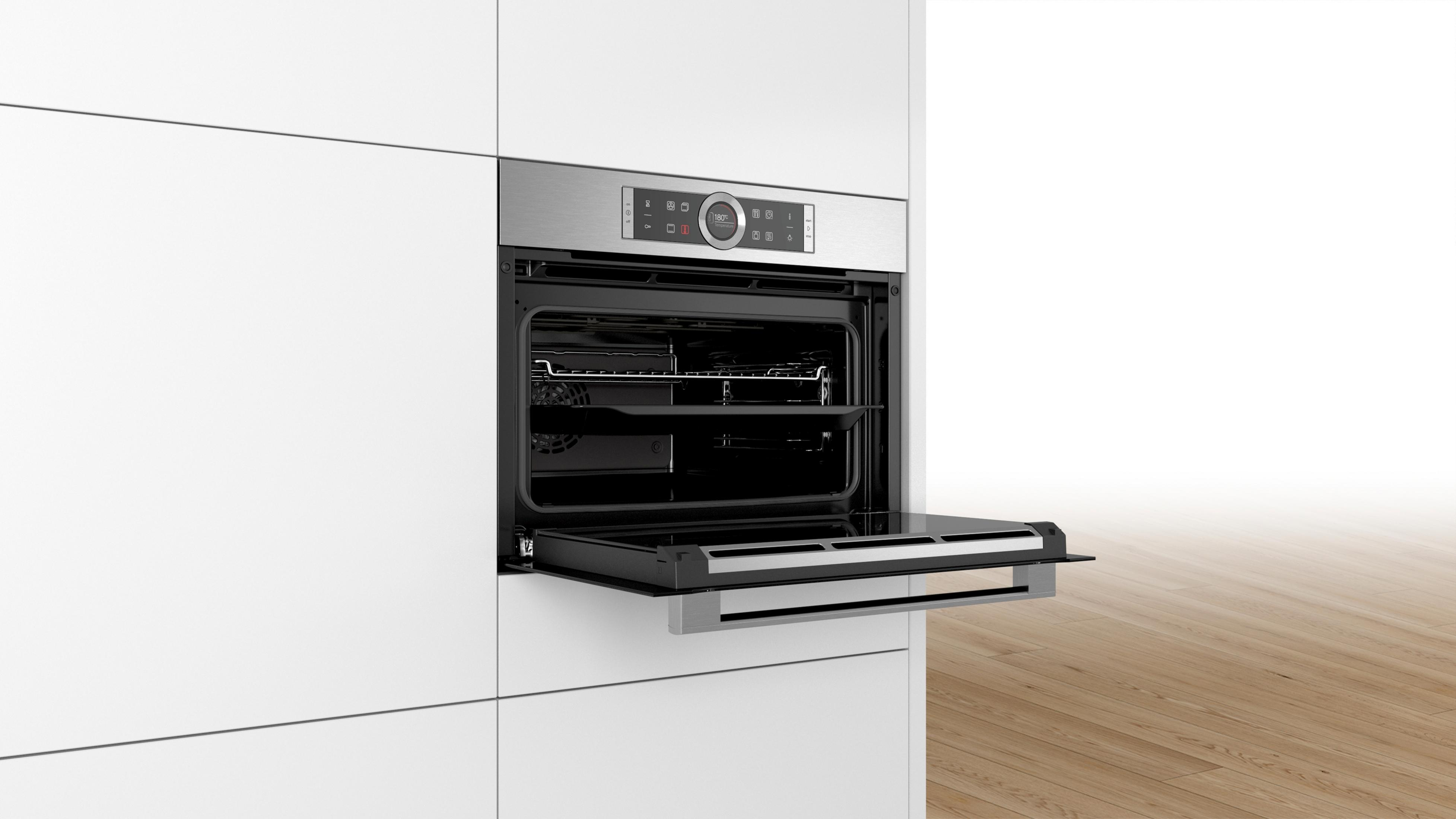 Four avec porte ouverte dans une cuisine blanche. Four et panneau de contrôle en acier inoxydable.