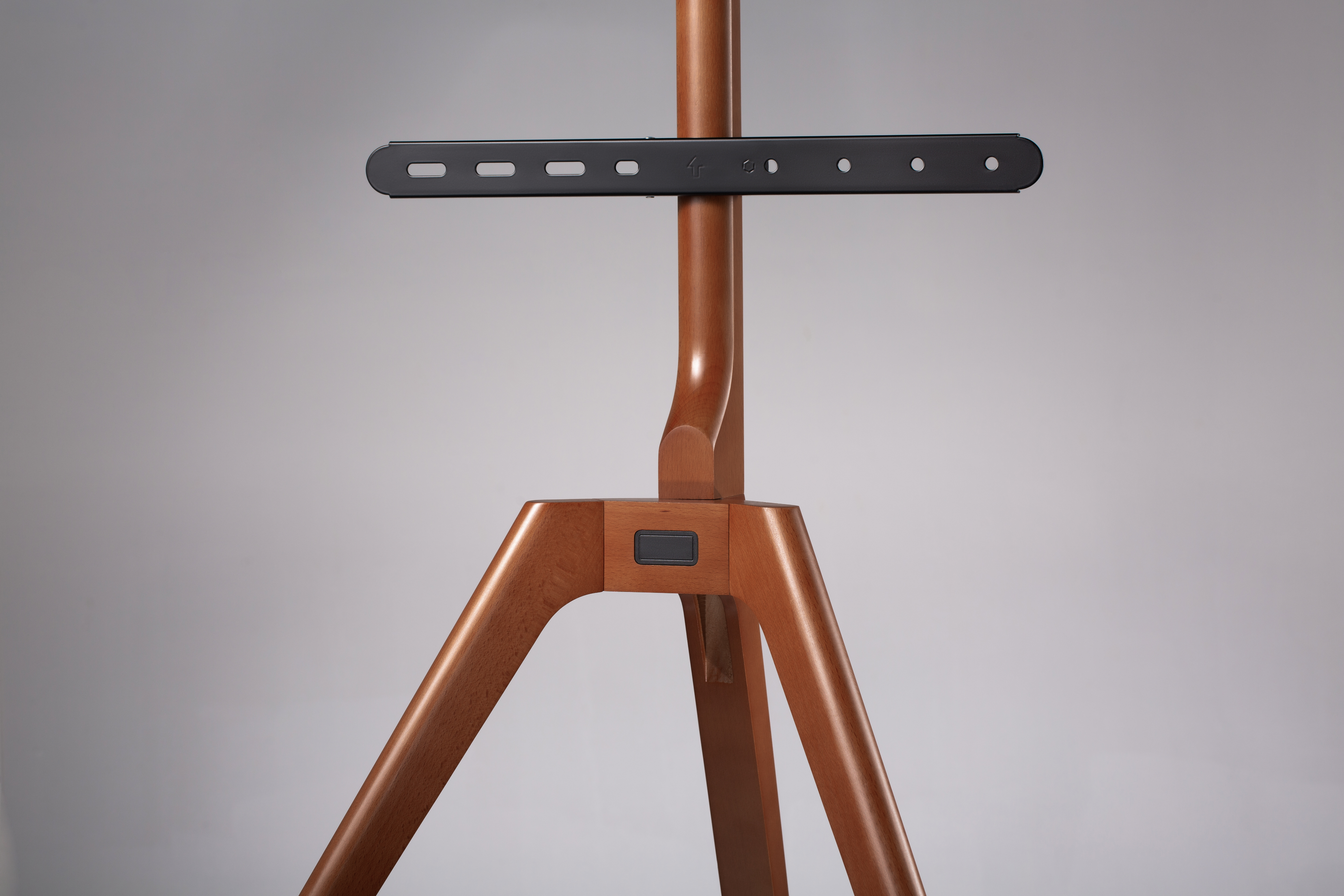 Soporte de TV de madera con soporte de montaje negro, sobre fondo gris.