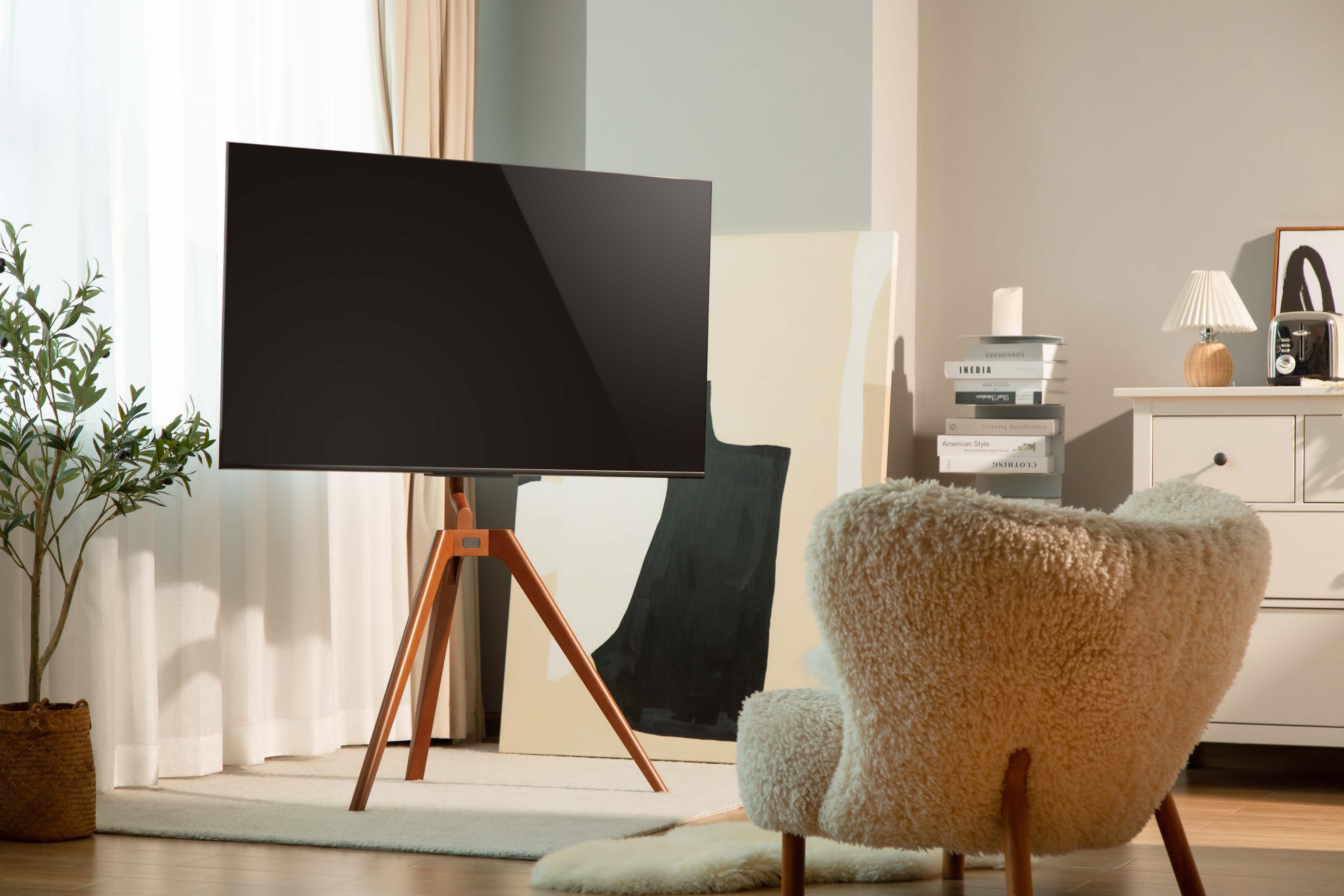 Una sala de estar con un televisor en un trípode de madera, una silla esponjosa y obras de arte.