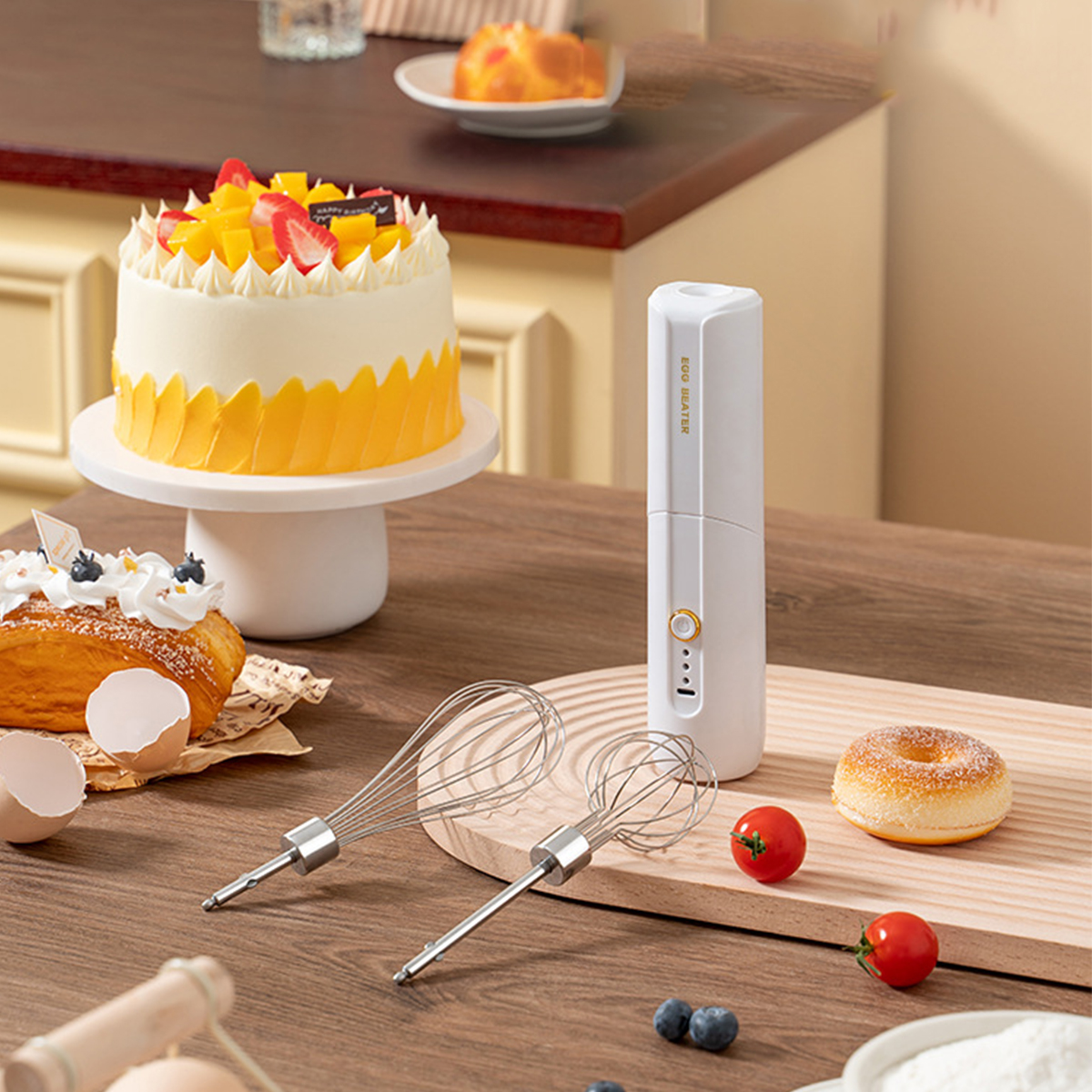 Ein Kuchen, Gebäck, ein elektrischer Mixer, Tomaten und ein Donut auf einem Tisch.