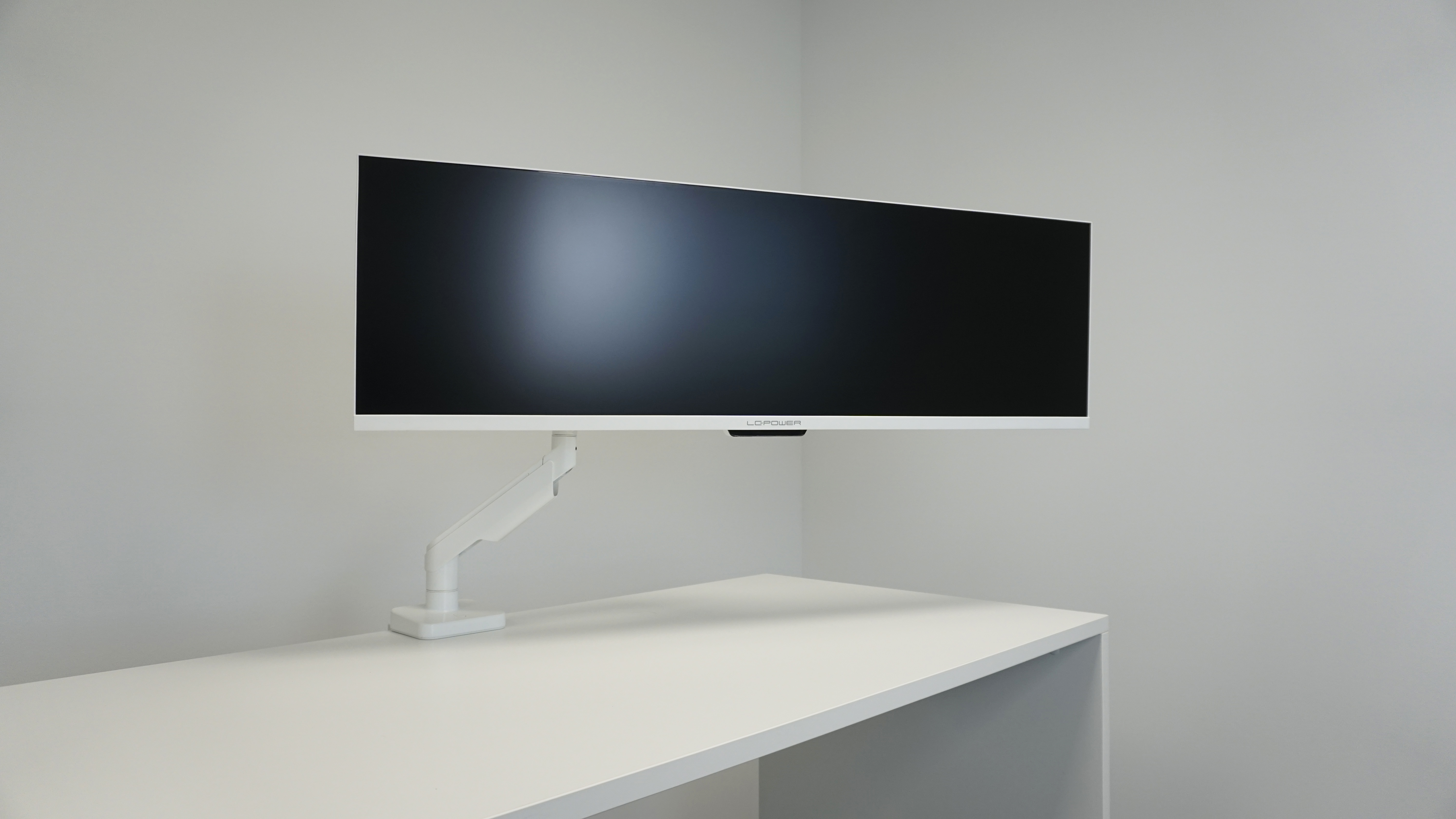 Ein weißer Monitor, montiert auf einem weißen Schreibtisch, mit einem weißen Arm.