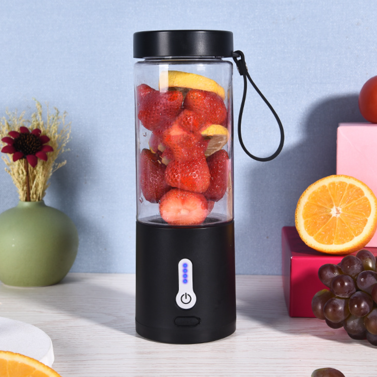 Mixer mit Erdbeeren und Zitrone. Hintergrund: Früchte und Vase auf hellem Untergrund.