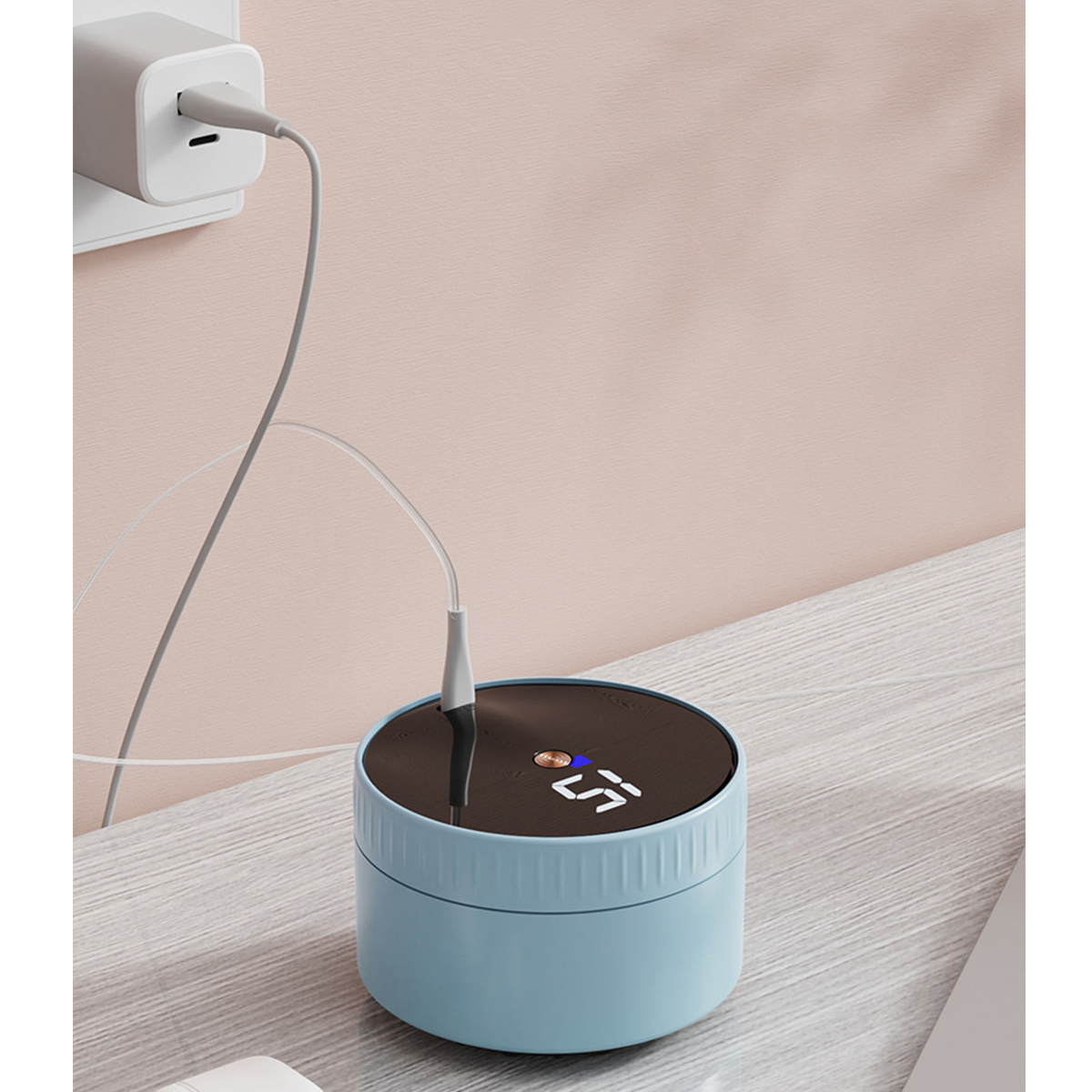 Ein blaues Ladegerät mit einer Anzeige, die '55' zeigt, und einem Kabel, das in eine Steckdose eingesteckt ist.