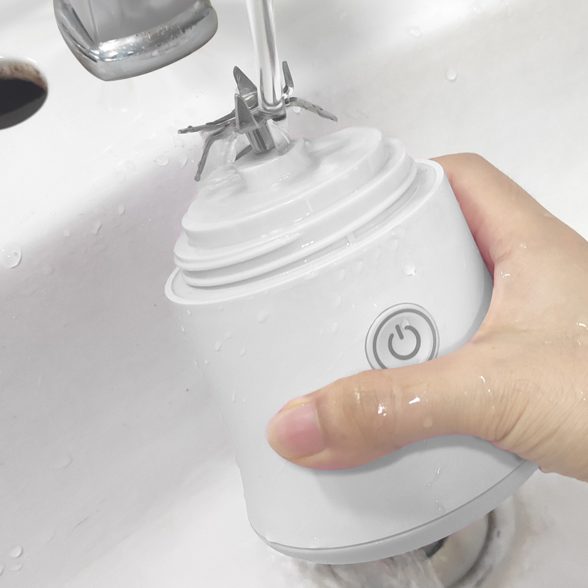 Eine Hand, die einen weißen Mixerfuß unter fließendem Wasser wäscht.