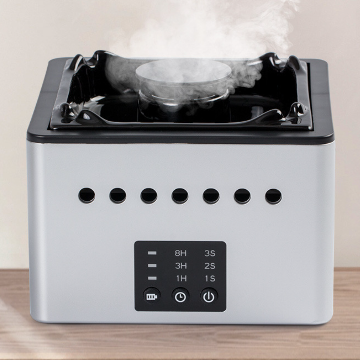 Kleiner silber-schwarzer Aromatherapie-Diffusor mit aufsteigendem Dampf und Bedienfeld.