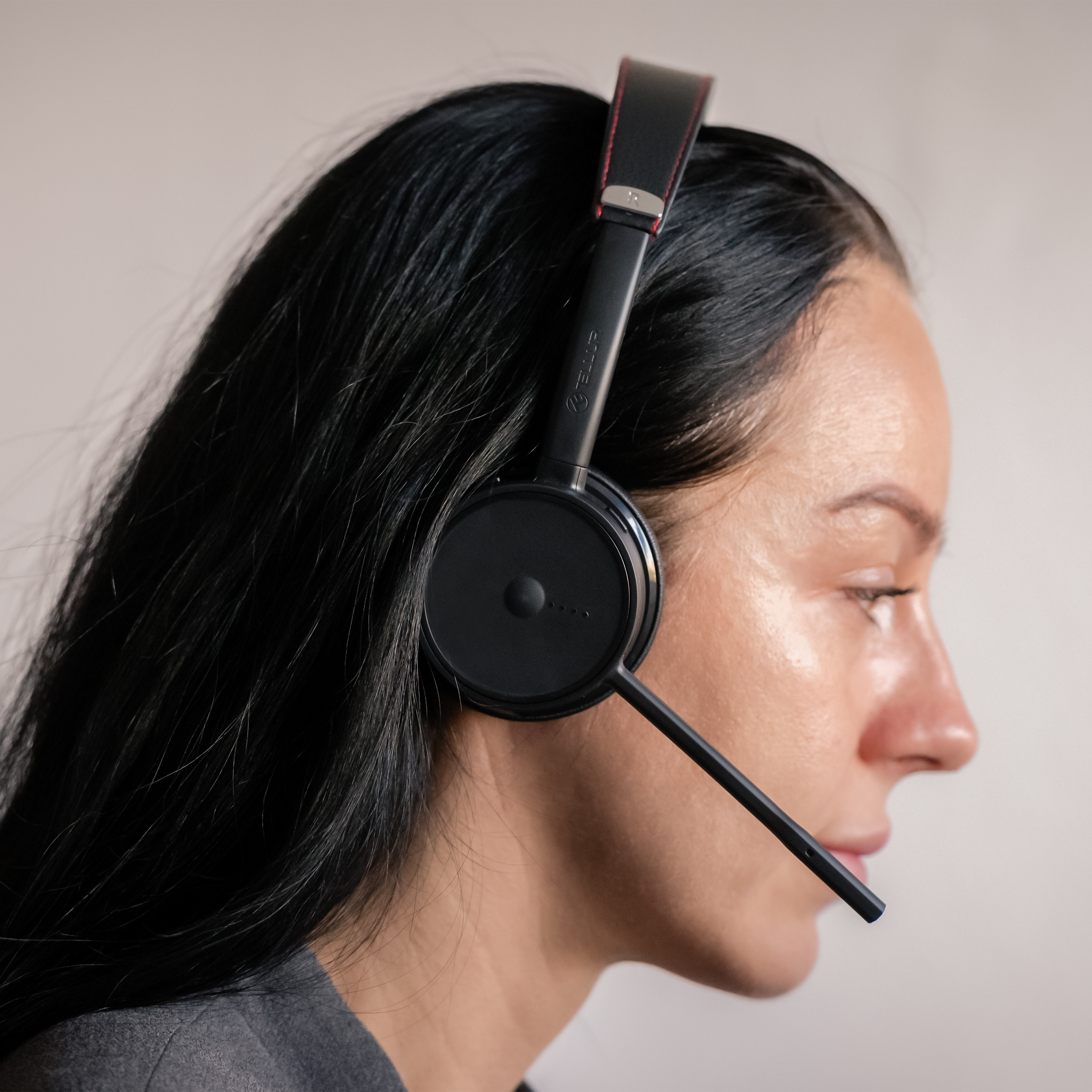 Eine Frau mit einem schwarzen Headset mit Mikrofon, Profilansicht, nach rechts blickend. Schwarzes Haar.