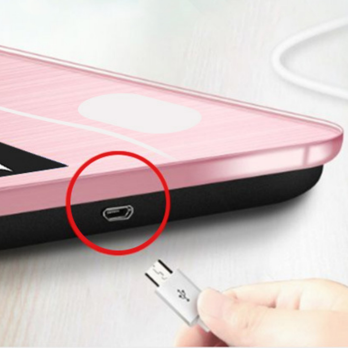 Nahaufnahme einer rosa Waage mit Ladeanschluss und USB-Kabel.