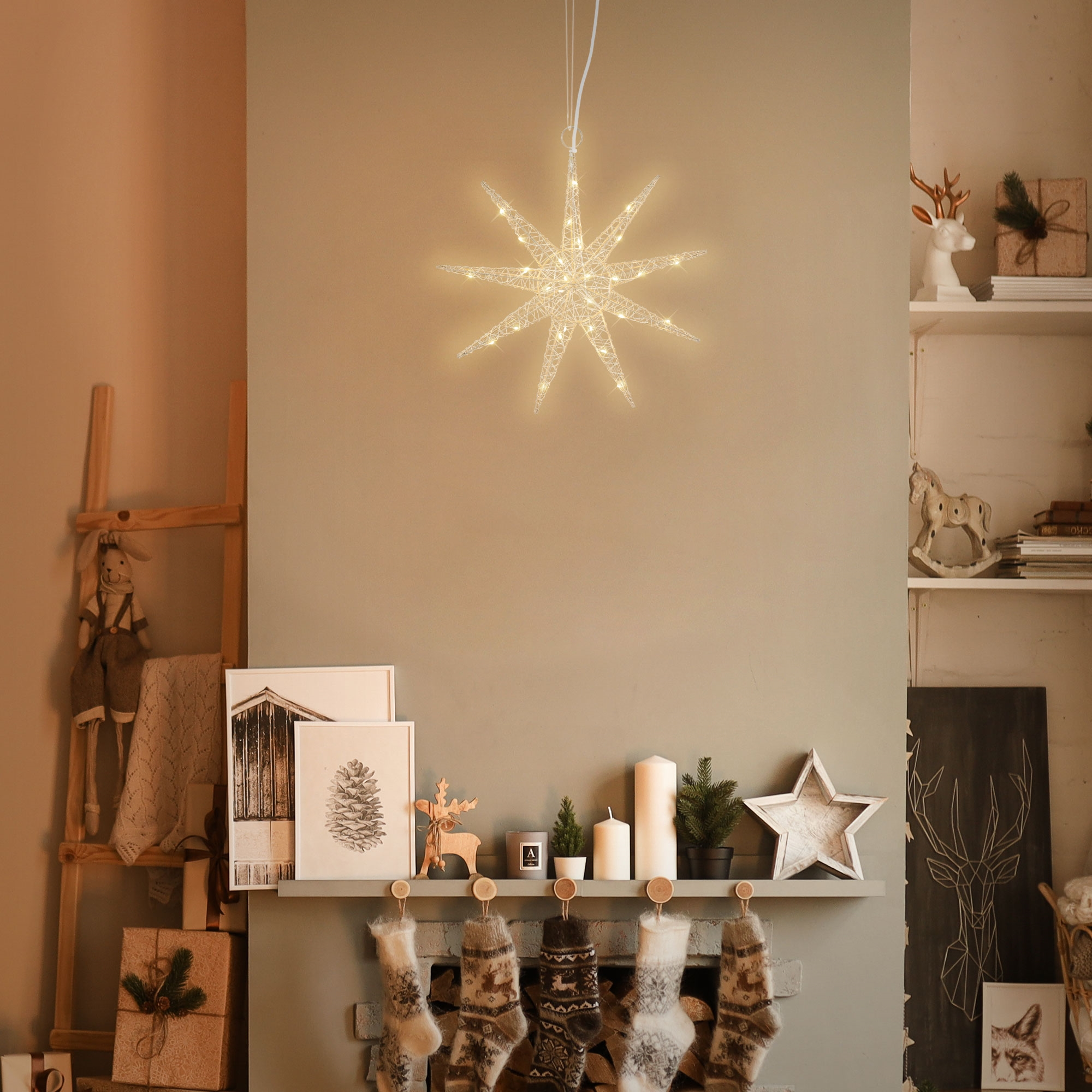 Beleuchteter goldener Drahtstern an der Wand. Kamin, Strümpfe und Dekoration im Bild.