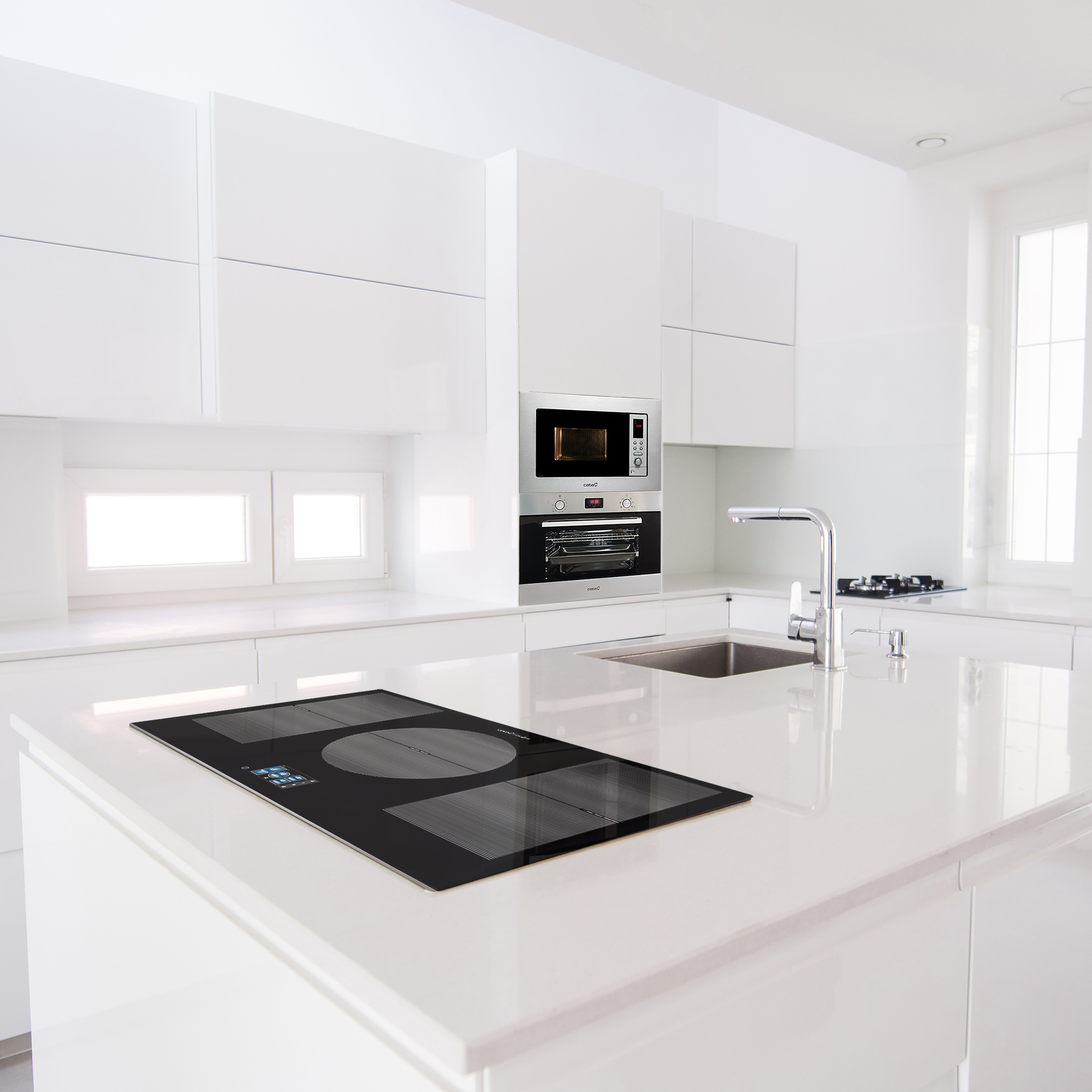 Isola cucina moderna con piano cottura nero integrato. Microonde e forno sopra. Armadi bianchi sullo sfondo.