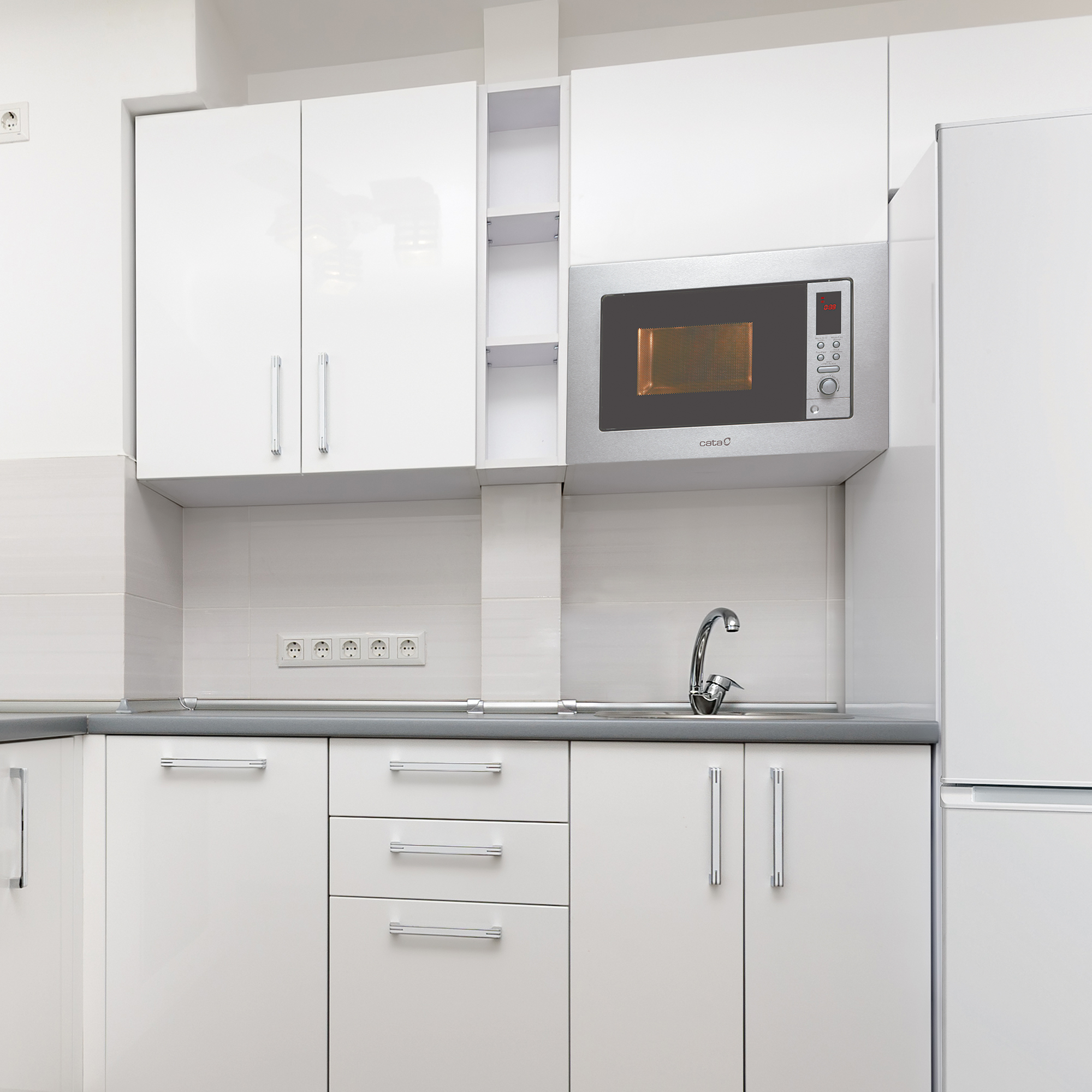 Una cucina moderna con mobili bianchi e un forno a microonde integrato nella parete.