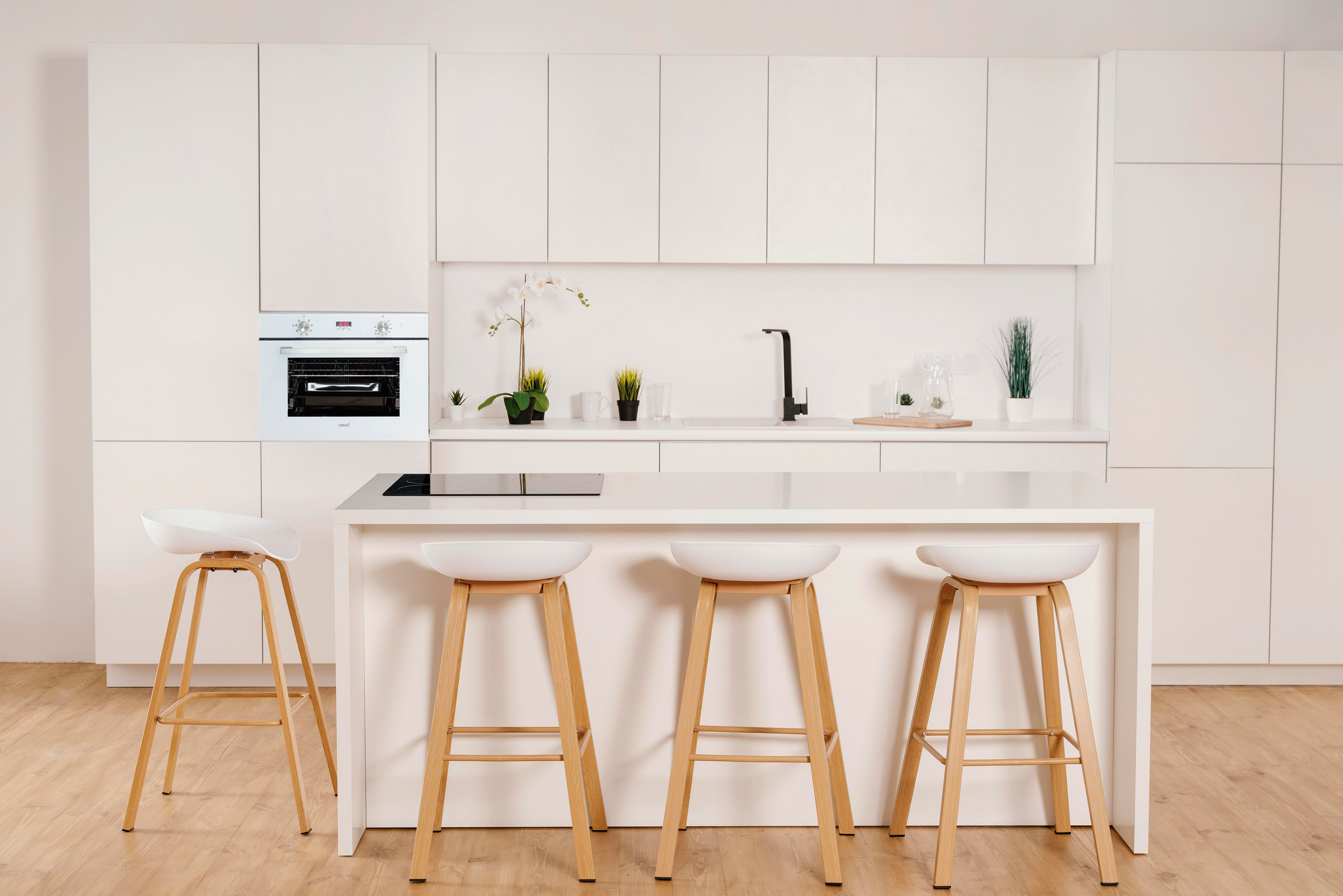 Una cocina moderna con gabinetes blancos, una isla blanca y un horno blanco empotrado.
