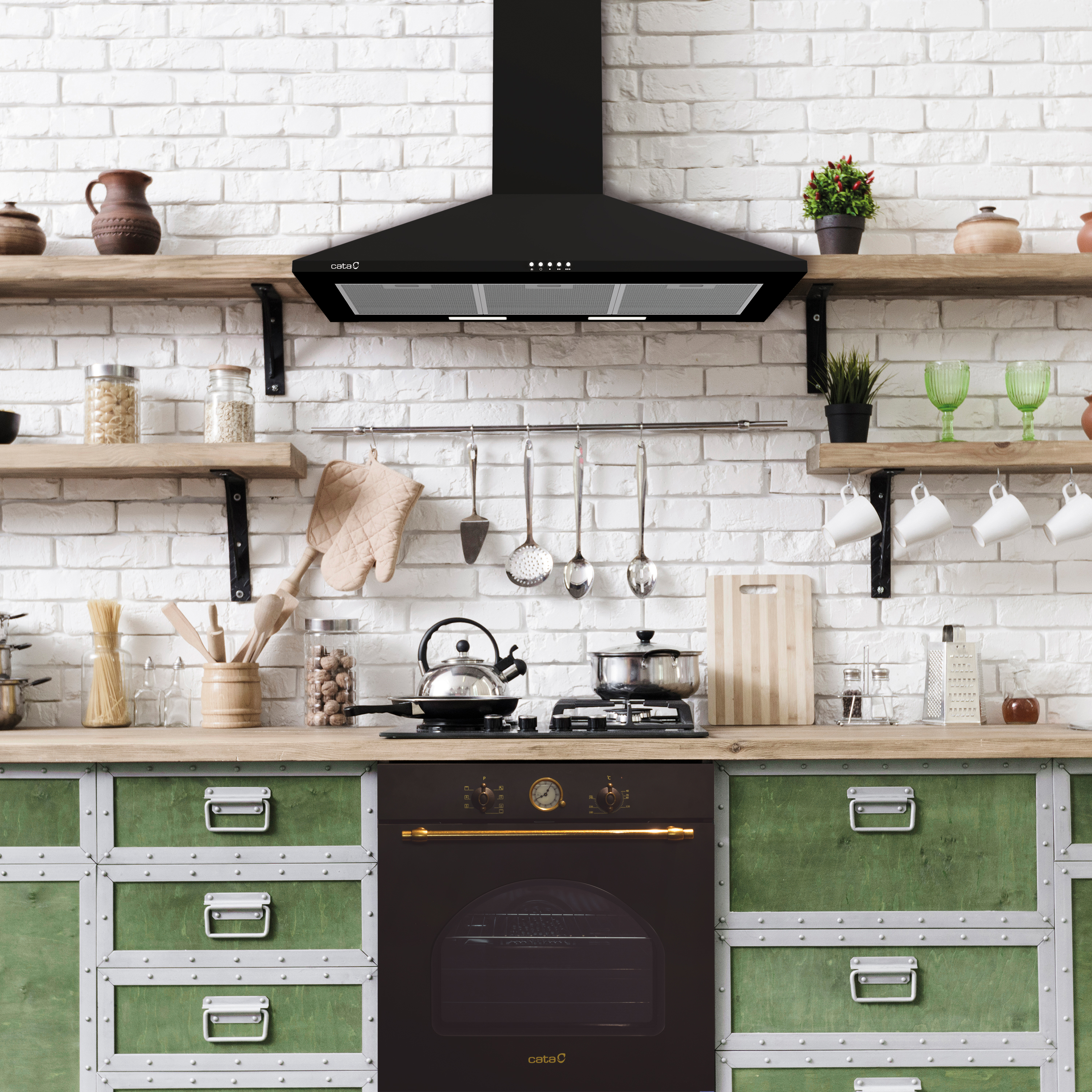 Kuchnia z czarnym okapem, kuchenką, piekarnikiem, drewnianymi półkami i zielonymi szafkami na tle ceglanej ściany.