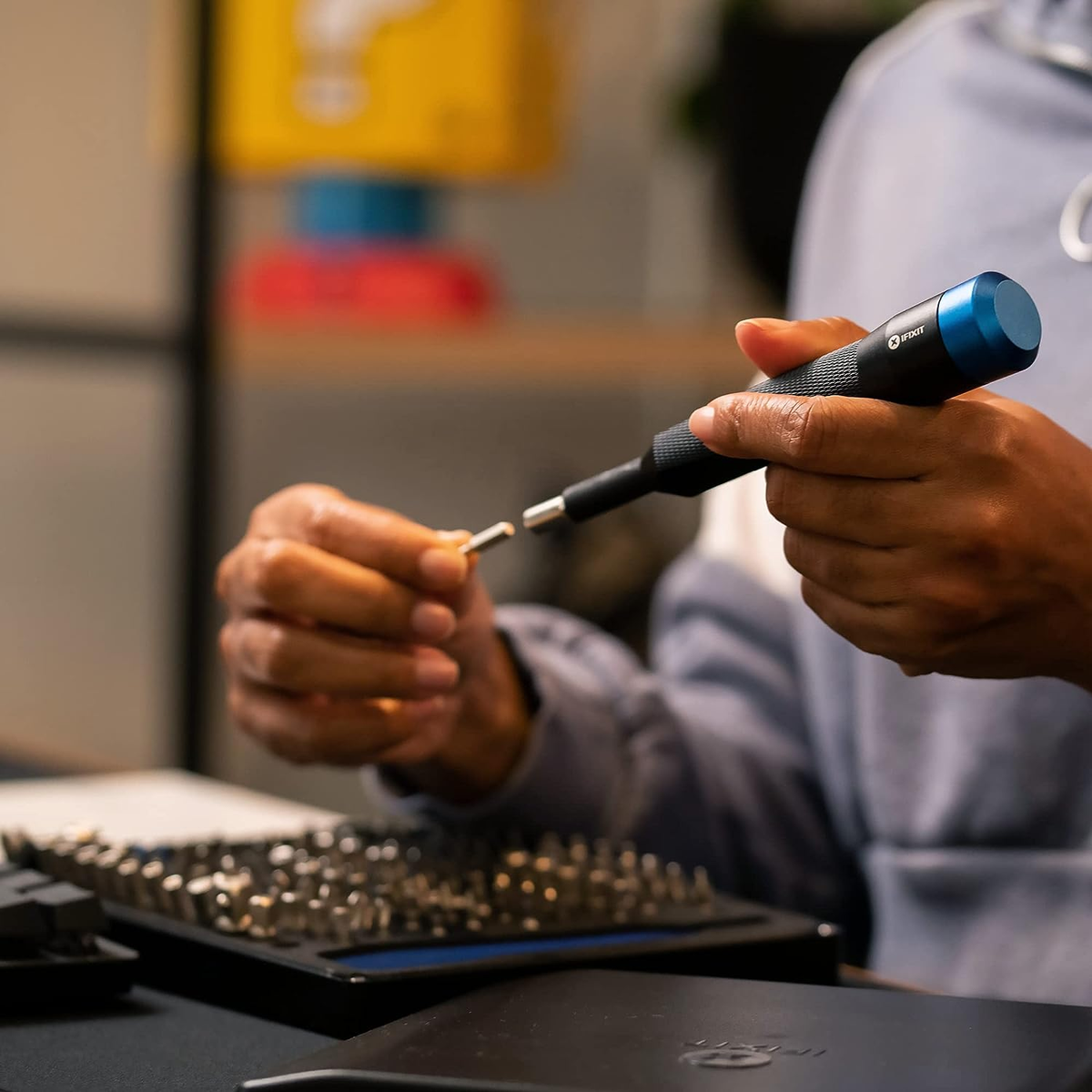 Person verwendet Schraubenzieher, um an elektronischen Teilen zu arbeiten. Blauer und schwarzer Schraubenzieher.