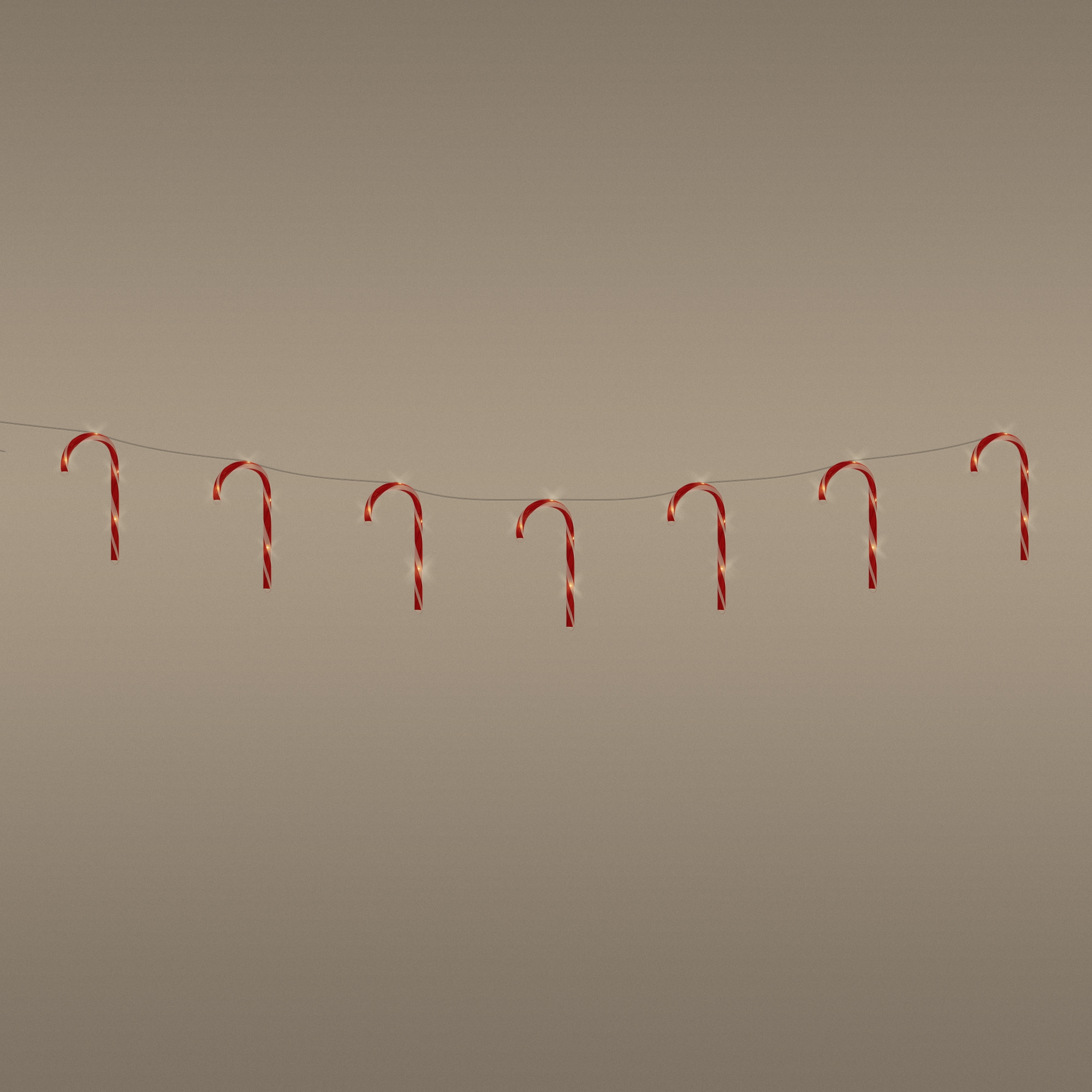 Zuckerstangenlichter. Rote und weiße Zuckerstangen auf einem Draht. Neutraler Hintergrund.