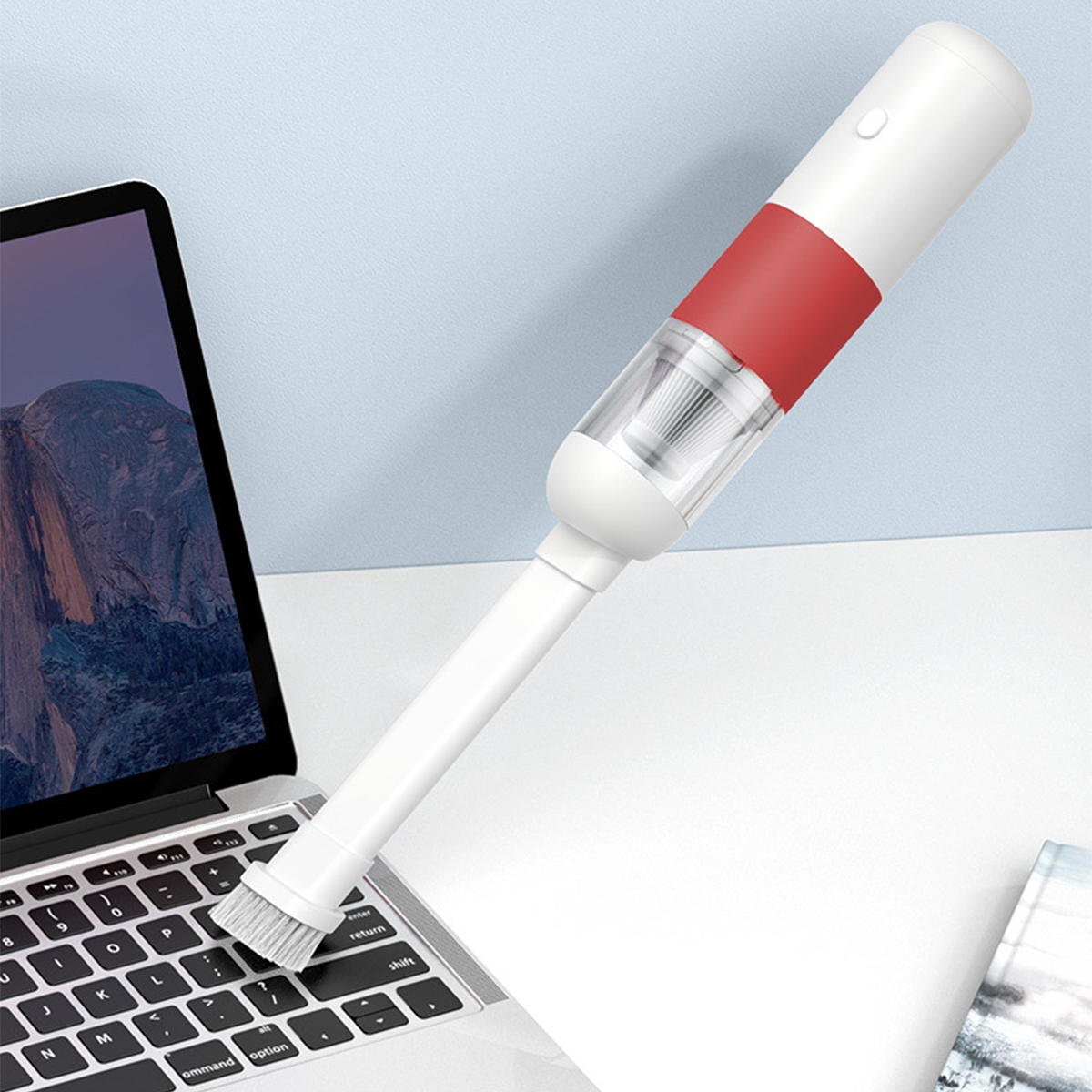 Odkurzacz ręczny z nasadką szczotkową na klawiaturze laptopa.