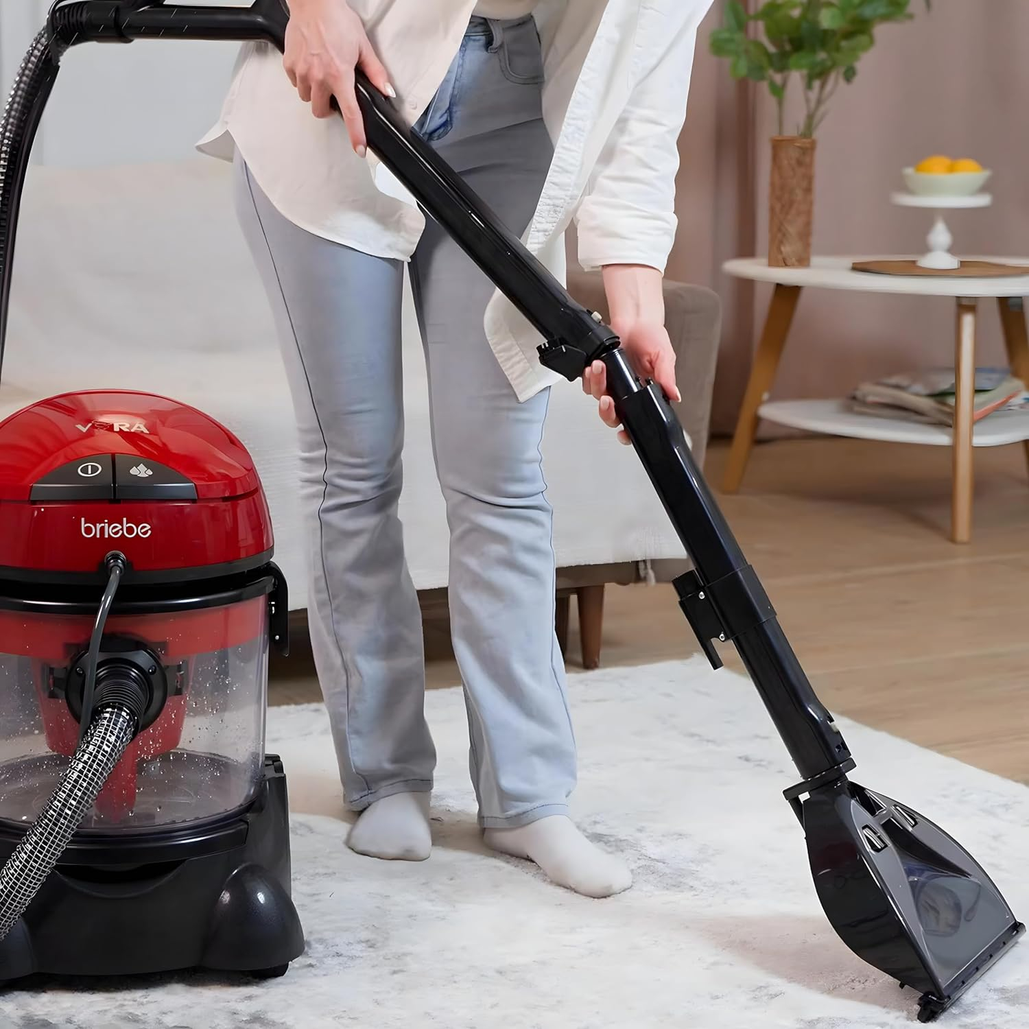 Frau, die mit einem rot-schwarzen Staubsauger einen Teppich saugt.