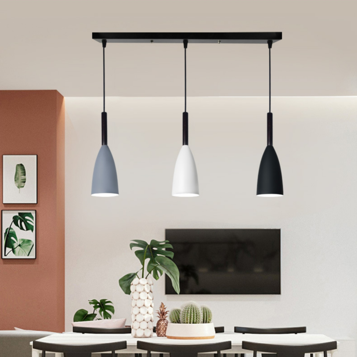 Drei hängende Pendelleuchten in einem Esszimmer. Eine grau, eine weiß und eine schwarz.