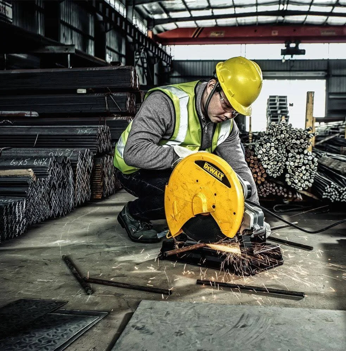 A worker cuts metal with a yellow Dewalt saw, sparks flying in a warehouse.