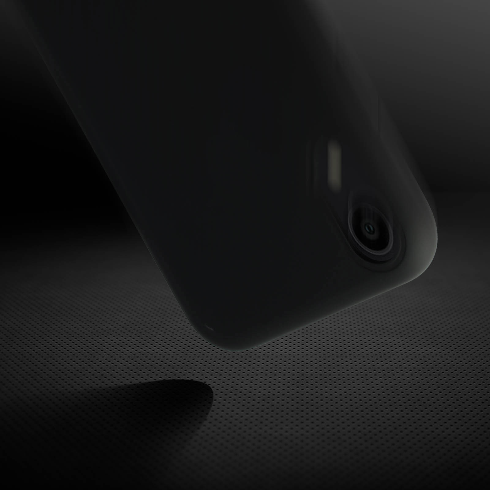 Een zwarte telefoon met een cameralens op een zwart oppervlak met textuur. Schaduw zichtbaar.