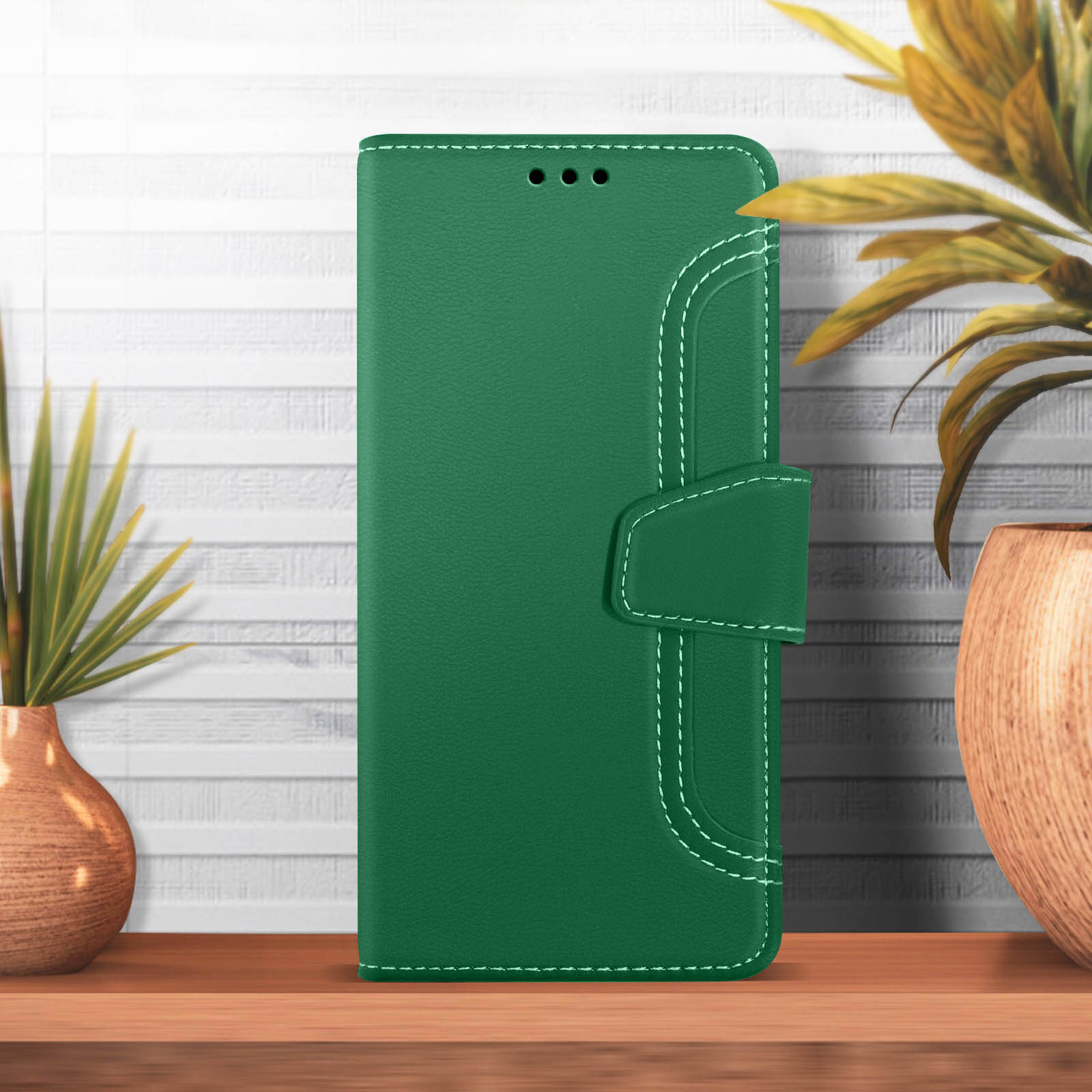 Custodia per telefono in pelle verde, chiusa, con cuciture bianche e chiusura, su legno.