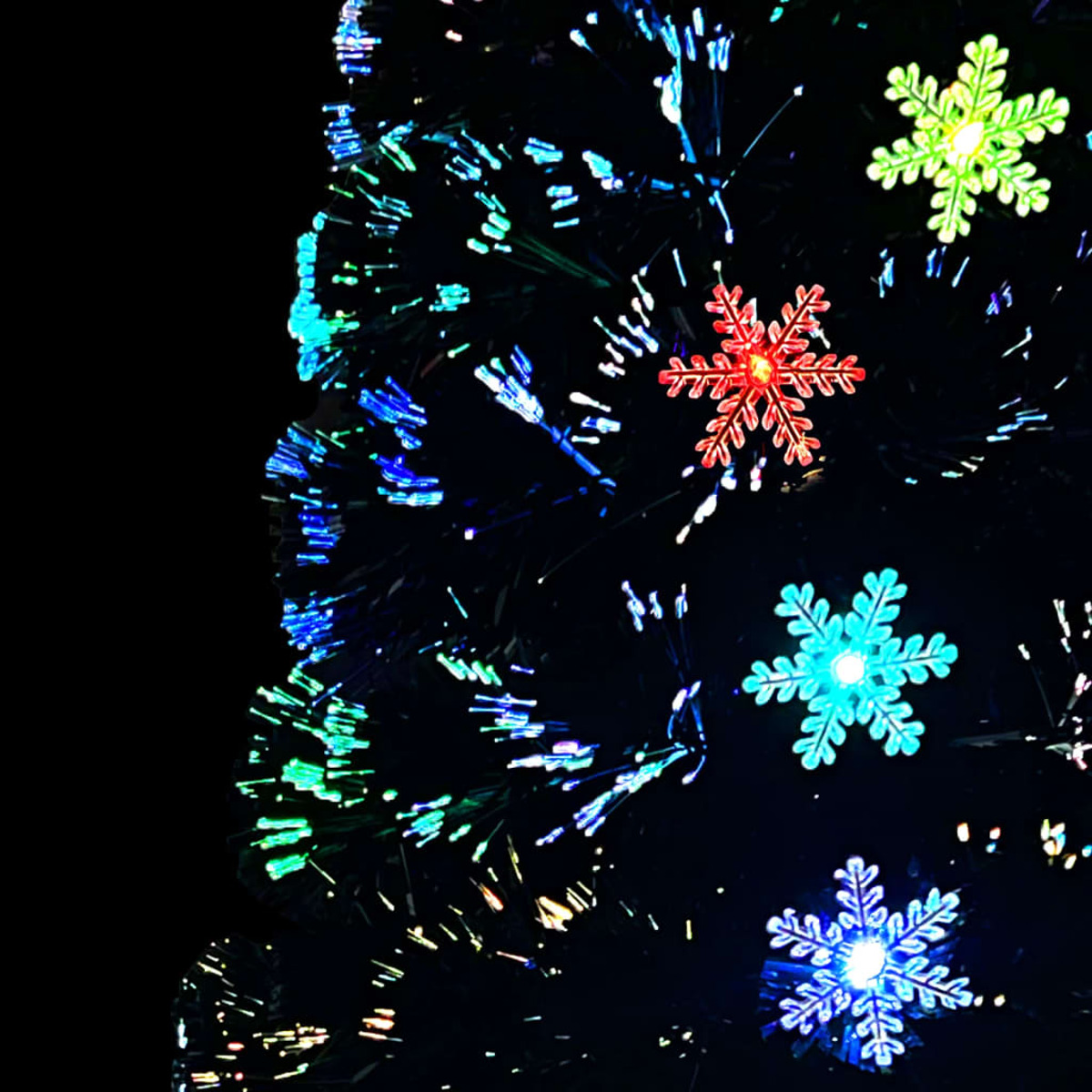 Nahaufnahme eines Weihnachtsbaums mit Schneeflockenlichtern. Schwarzer Hintergrund.