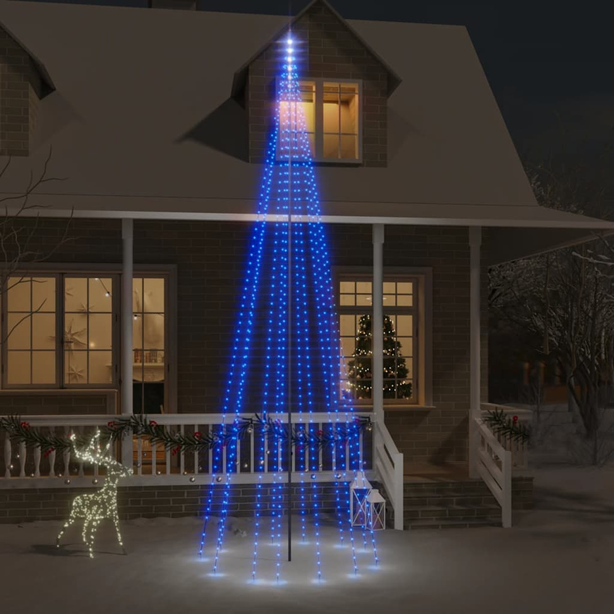 Ein Weihnachtsbaum aus blauen Lichtern vor einem Haus bei Nacht, mit Hirschdekoration.