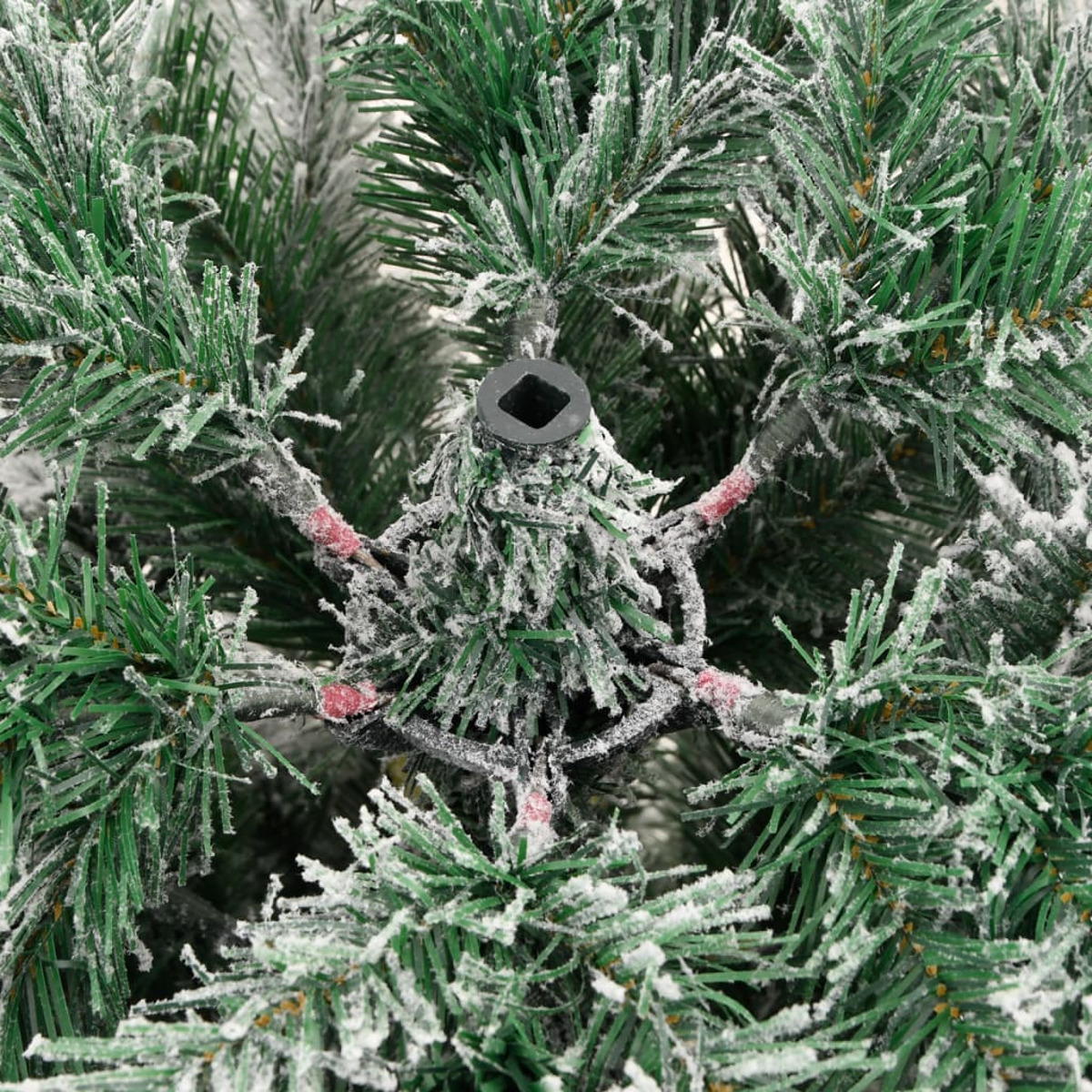 Nahaufnahme des zentralen Stammes eines Weihnachtsbaums mit schneebedeckten Ästen und einem Metallträger.