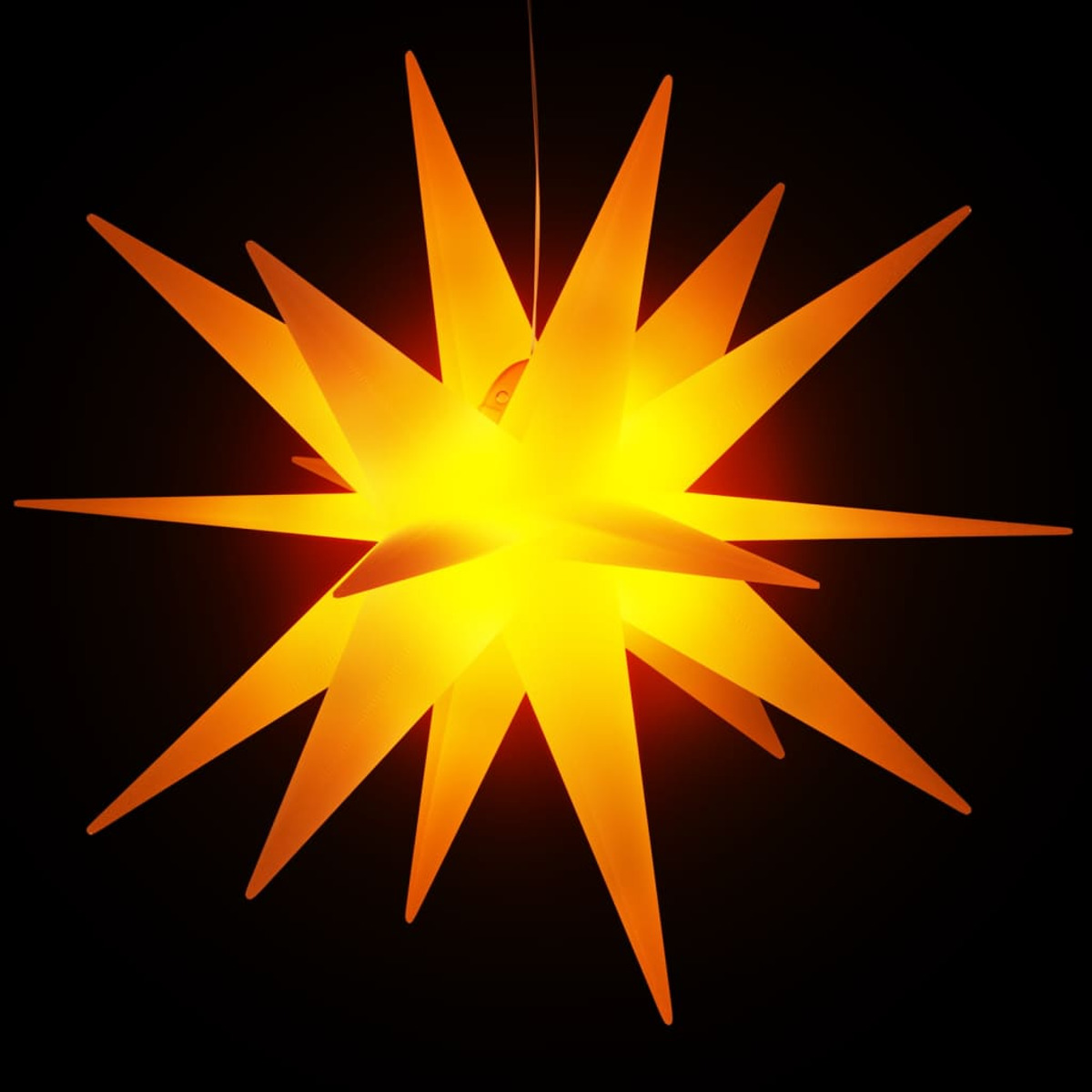 Sternförmige Leuchte mit hellem orangefarbenem Glühen vor schwarzem Hintergrund.