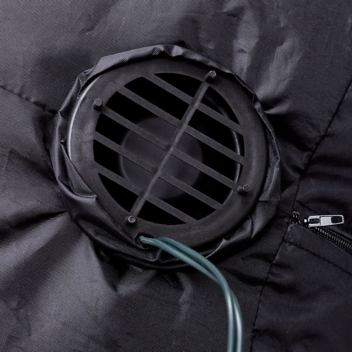 Nahaufnahme eines schwarzen Ventilators mit grünem Kabel und schwarzem Stoffbezug.