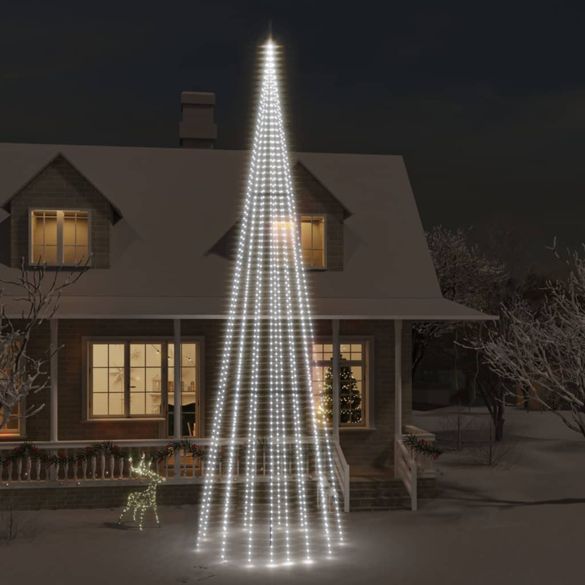 Ein Weihnachtsbaum aus Lichtern vor einem Haus bei Nacht. Schnee.