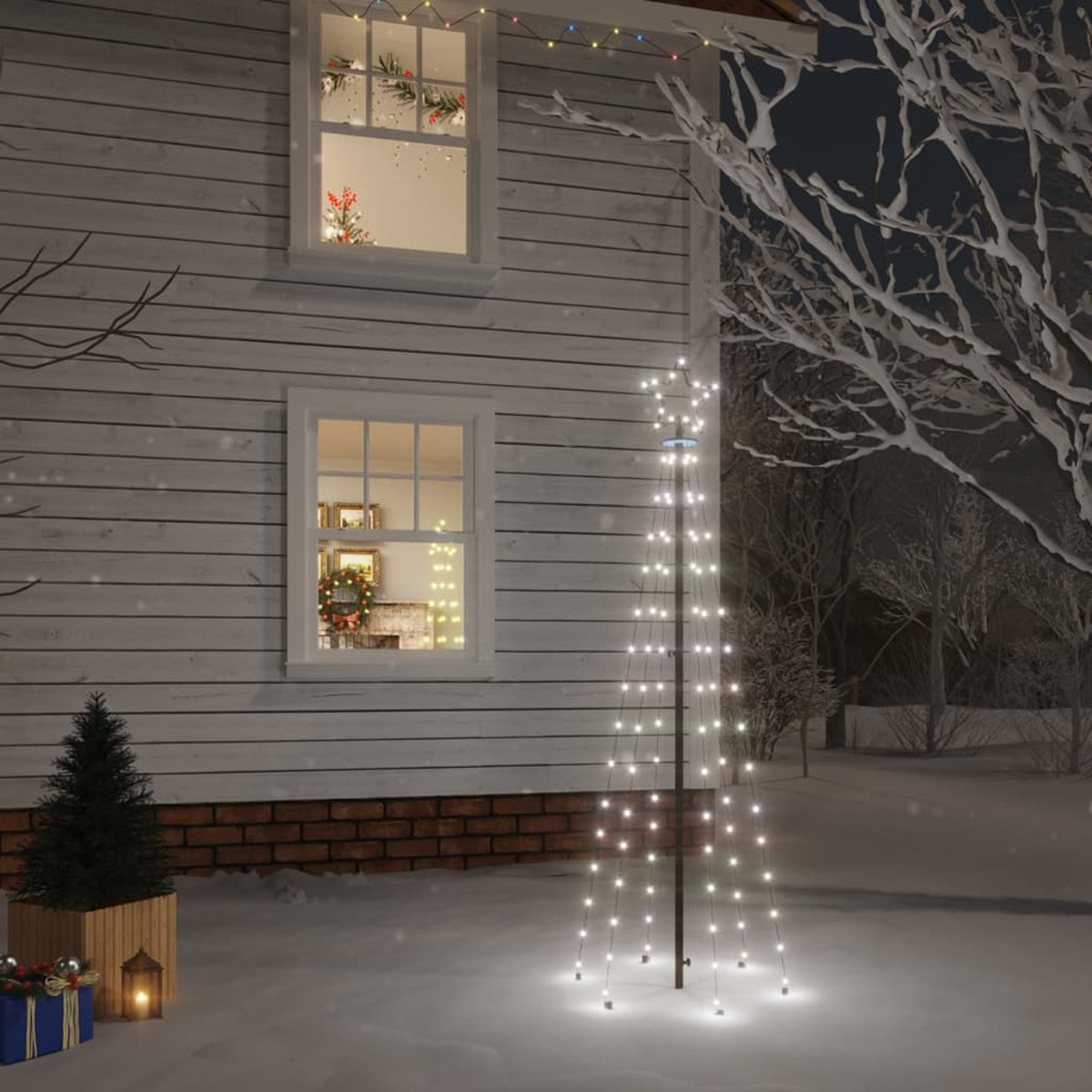 Ein Haus mit beleuchteten Fenstern, einer Lichterkette und einer weihnachtsbaumförmigen Lichteranzeige im schneebedeckten Garten.