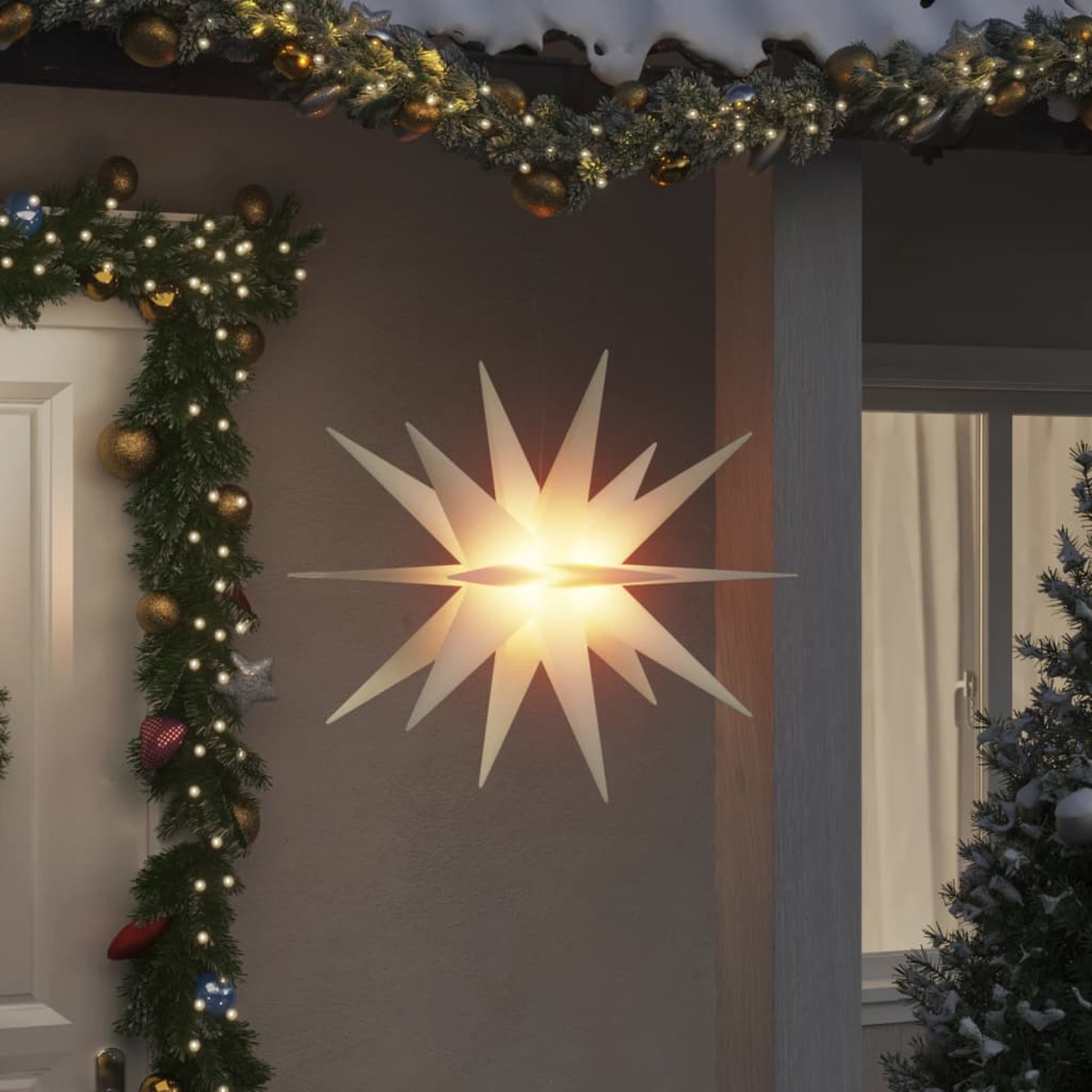 Sternförmige Weihnachtsbeleuchtung. Sie leuchtet weiß und hängt über einer Haustür.