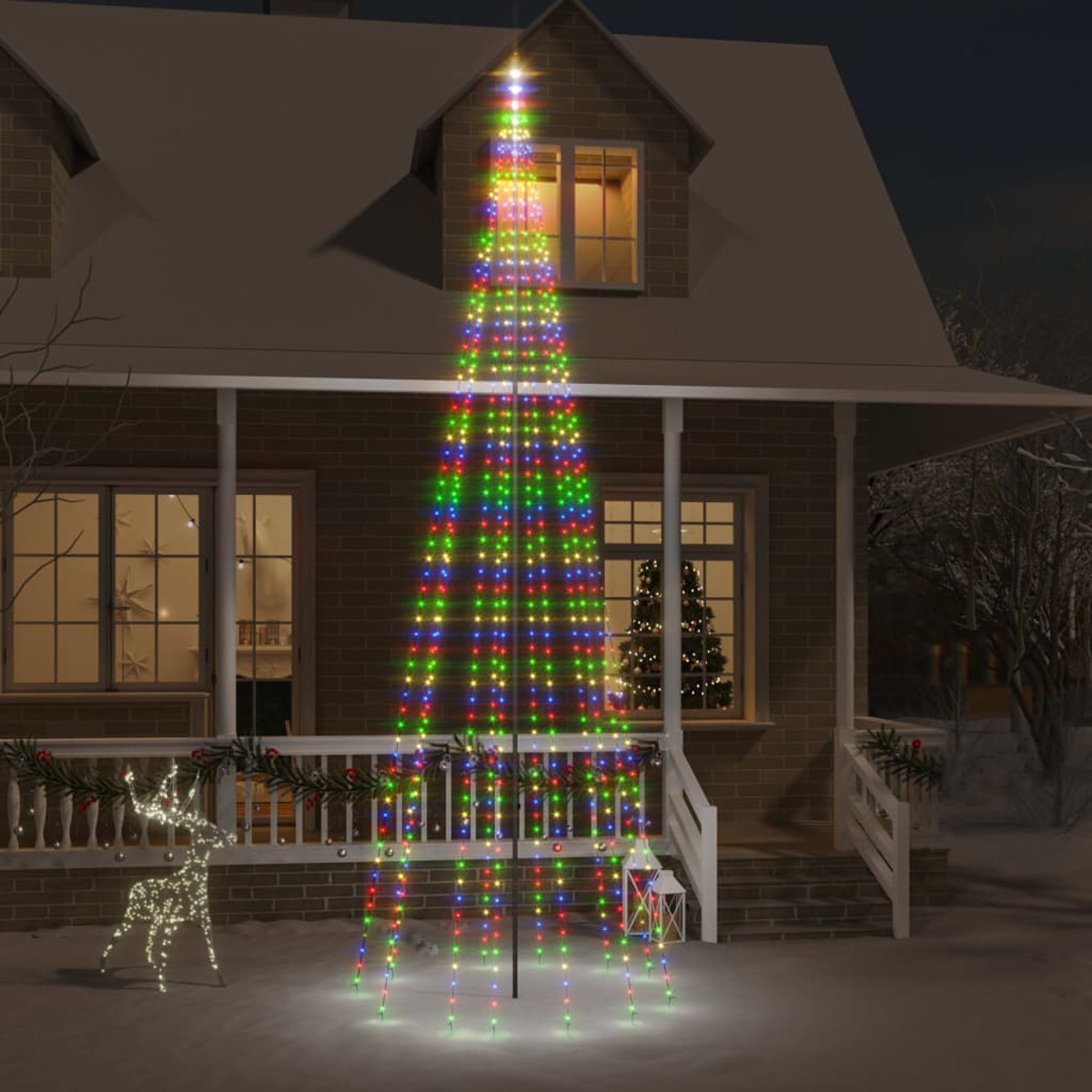 Weihnachtsbaum mit bunten Lichtern vor Haus bei Nacht.