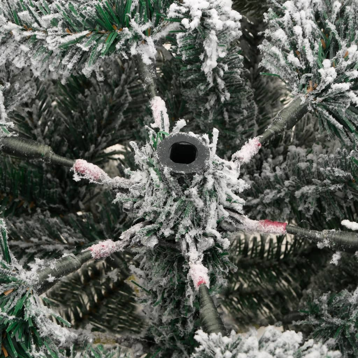 Nahaufnahme eines grünen Weihnachtsbaums mit Schnee-Effekt, der Äste und die zentrale Halterung zeigt.