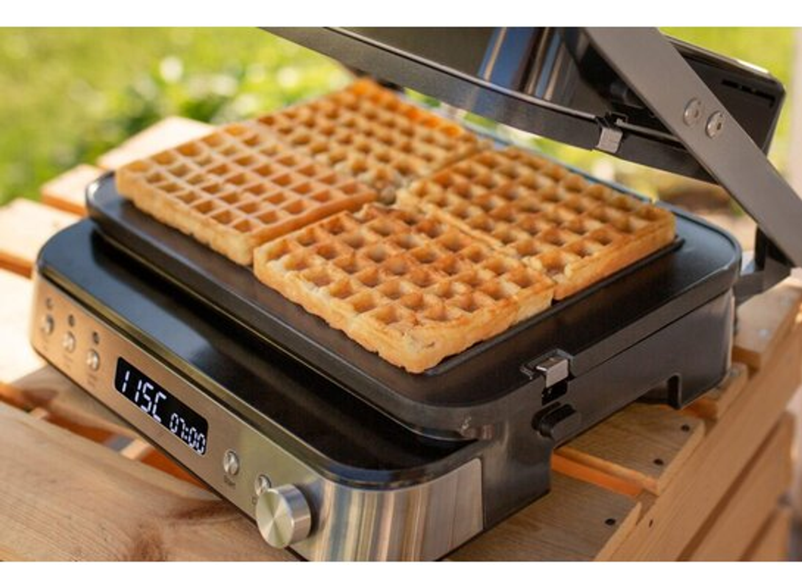Waffeleisen mit vier Waffeln. Anzeige: 115C und 01:00. Hintergrund ist unscharf grün.