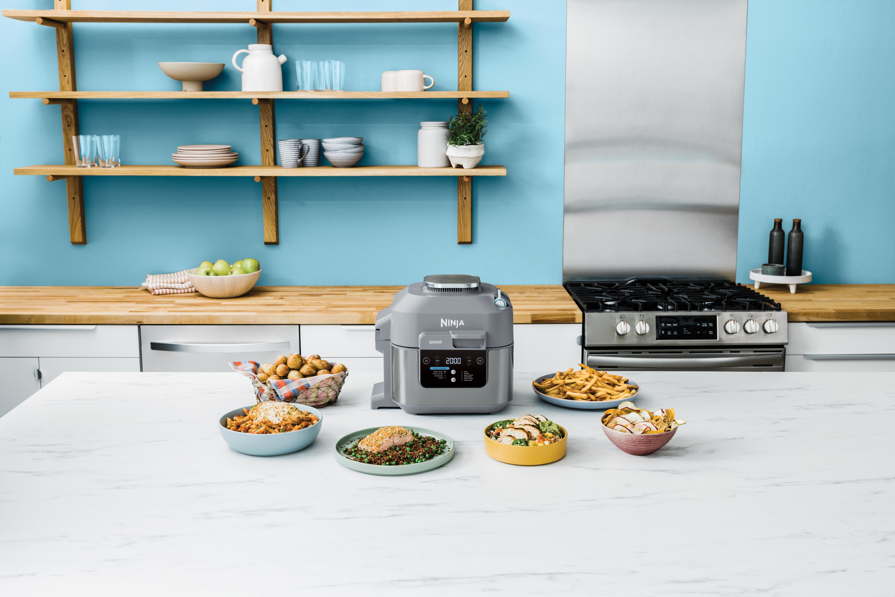 Kitchen scene with a Ninja multi-cooker, various dishes, and a stainless steel range.