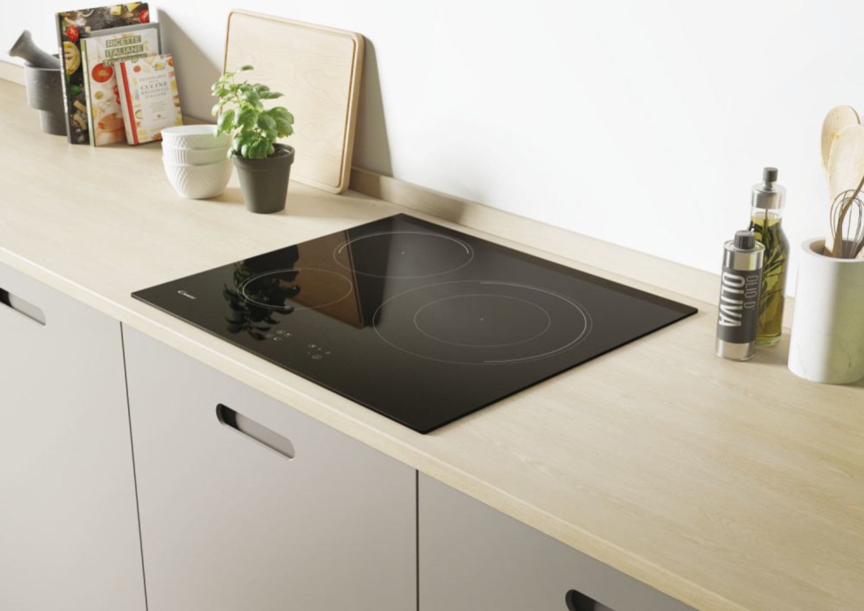 Encimera eléctrica negra sobre una encimera de madera. Ambiente de cocina con libros y planta.