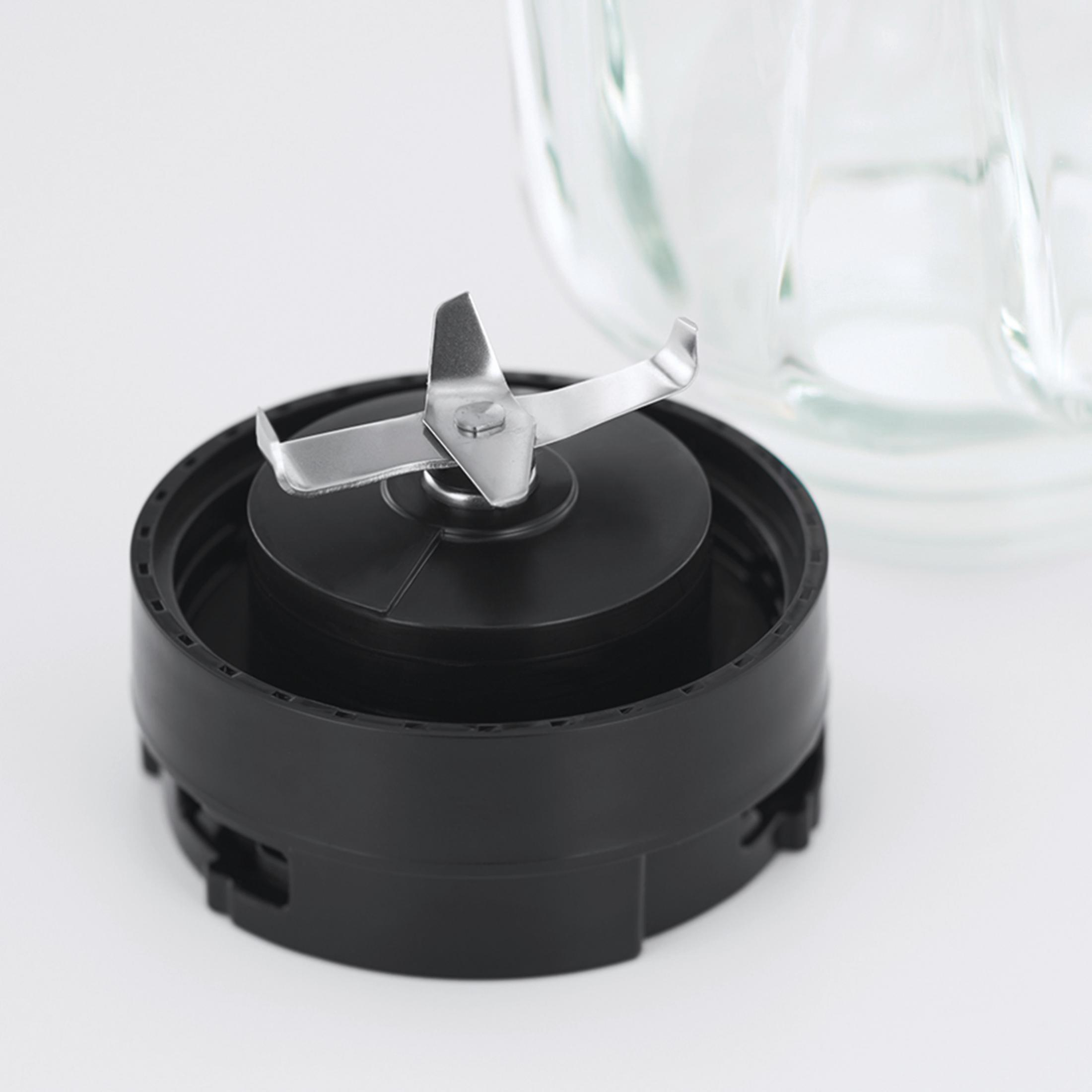 Bıçak eki ve cam kavanozlu bir blender tabanı. Blender beyaz bir yüzey üzerinde.