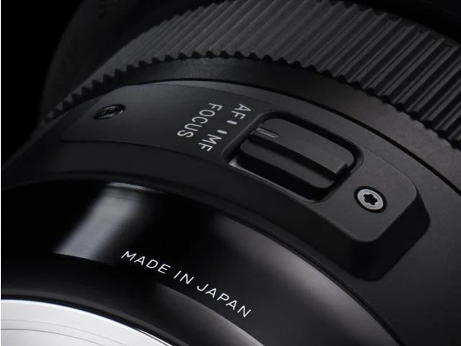 Primer plano de lente de cámara negra con marcas de enfoque y Made in Japan.