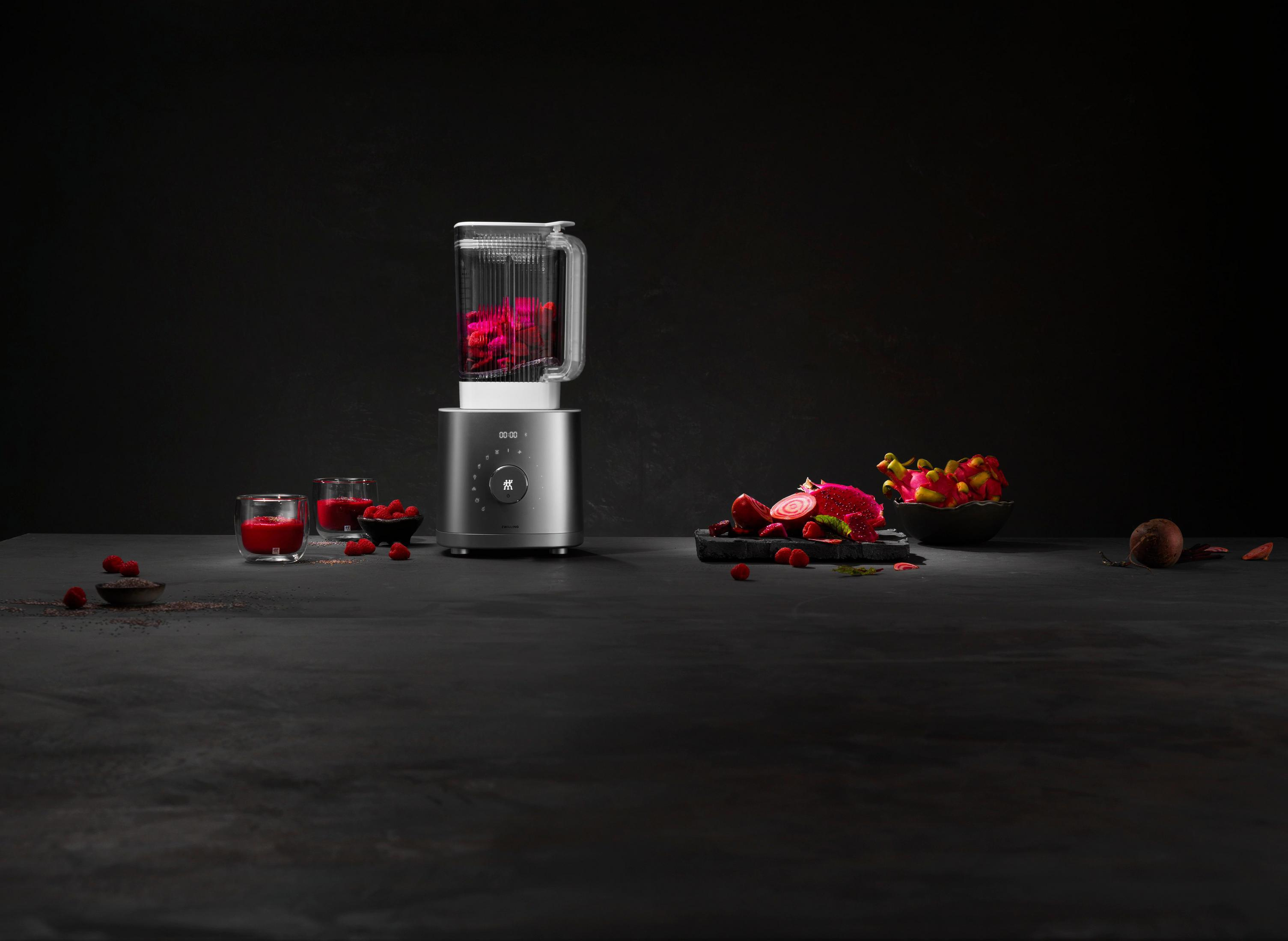 Blender z różowymi składnikami i ciemnym tłem ze składnikami na ciemnej powierzchni.