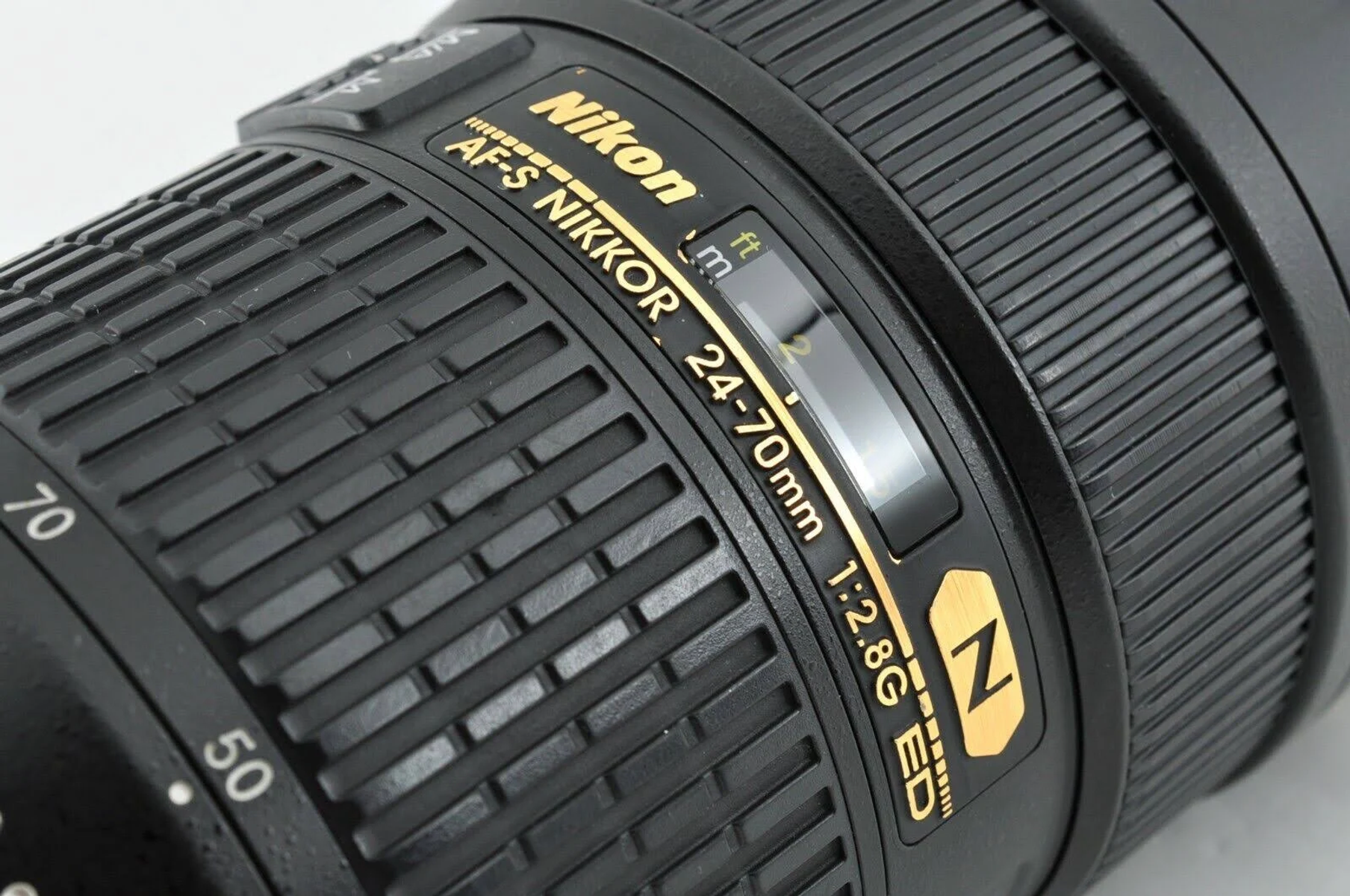 Nahaufnahme eines Nikon-Objektivs mit goldenem Text: 24-70mm 1:2.8G ED und dem Nikon-Logo.