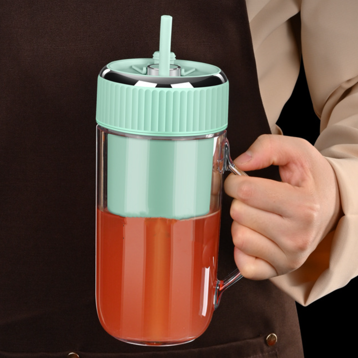 Eine Person hält einen grünen und durchsichtigen Smoothie-Becher mit Strohhalm. Rote Flüssigkeit drin.