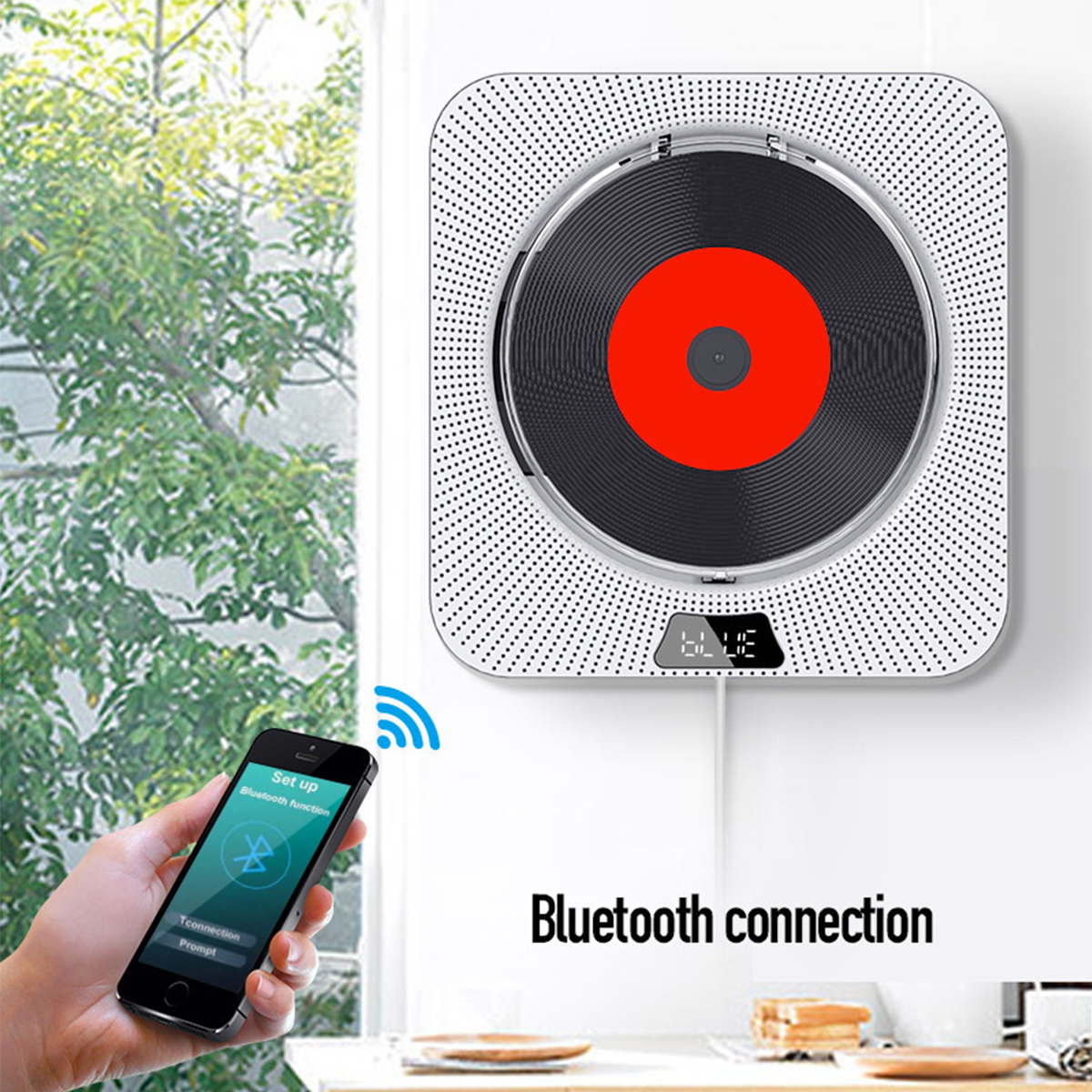 Weißer, an der Wand montierter CD-Player mit roter CD. Telefon in der Nähe zeigt Bluetooth-Setup.
