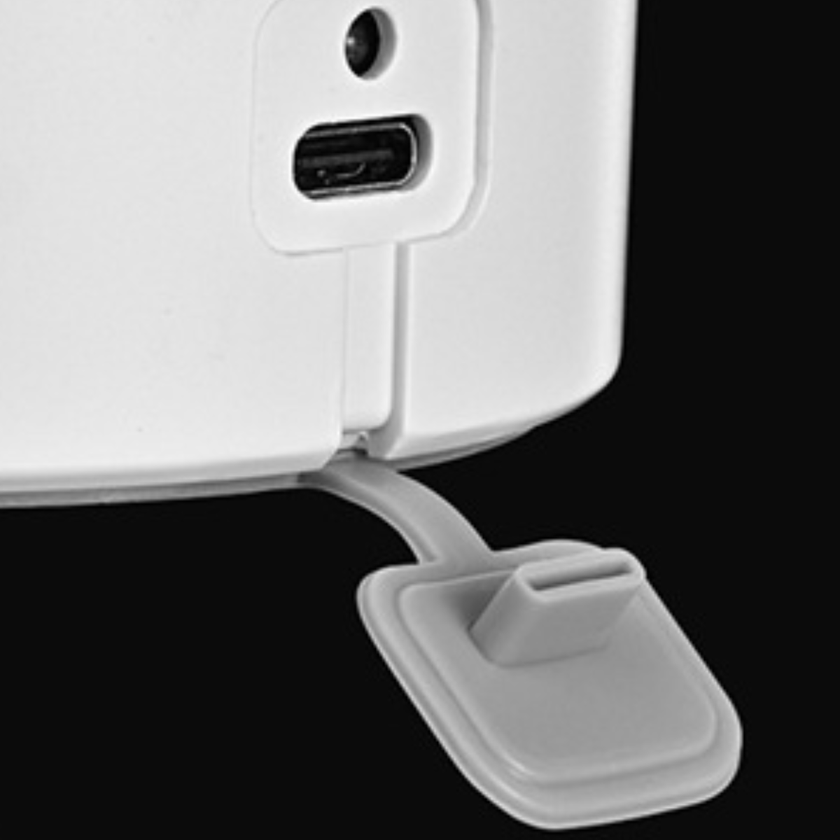 Nahaufnahme eines weißen Geräts mit USB-Anschluss und grauer Staubschutzabdeckung, auf dunklem Hintergrund.
