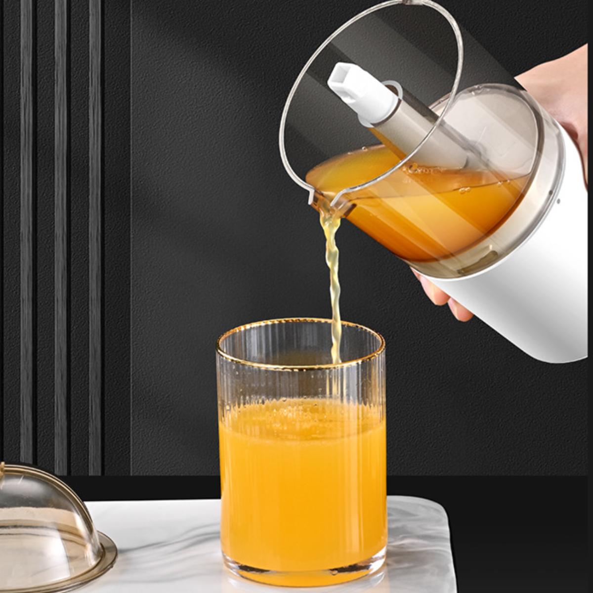 Saft wird aus einem Entsafter in ein Glas gegossen. Das Glas steht auf einer weißen Oberfläche.