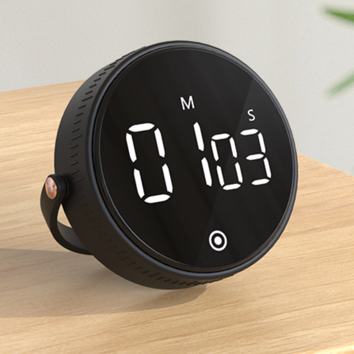 Schwarzer digitaler Küchentimer, der 0 Minuten und 1:03 Sekunden anzeigt. Er steht auf einer Holzoberfläche mit einem Griff.