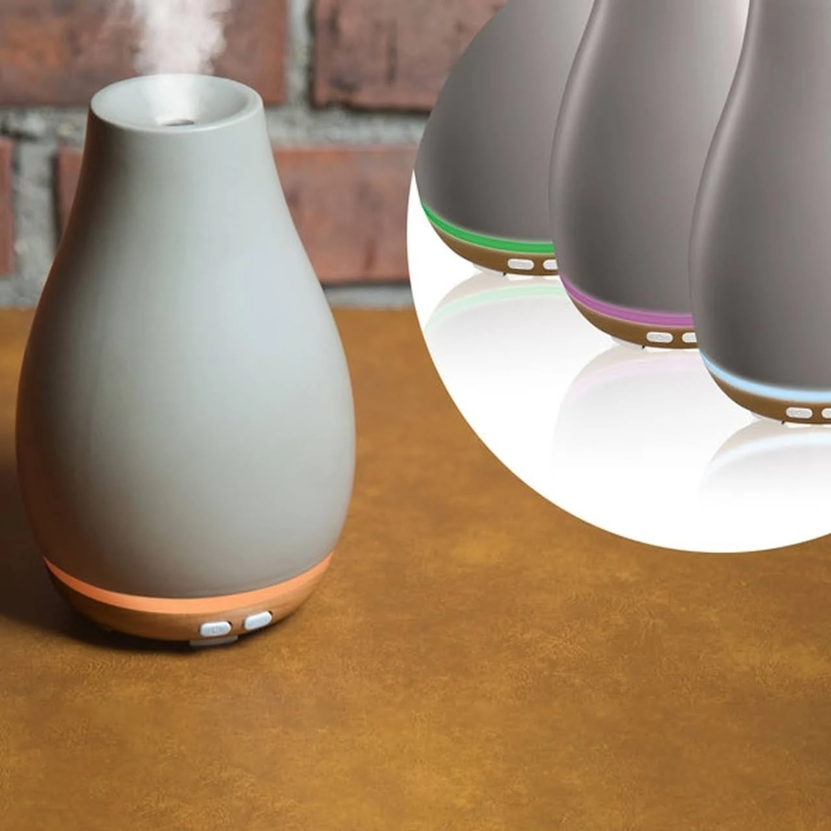 Drei graue Aromadiffusoren mit farbigen Lichtern an der Basis. Brauner Holztisch.