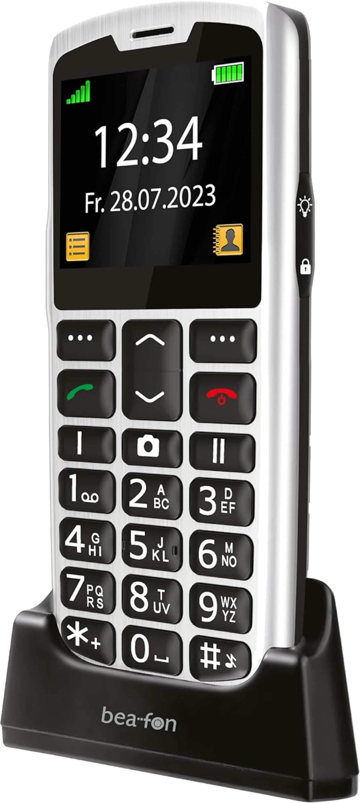 Ein weißes und schwarzes Mobiltelefon mit großen Tasten, das Zeit und Datum anzeigt. Es befindet sich in einer Ladestation.