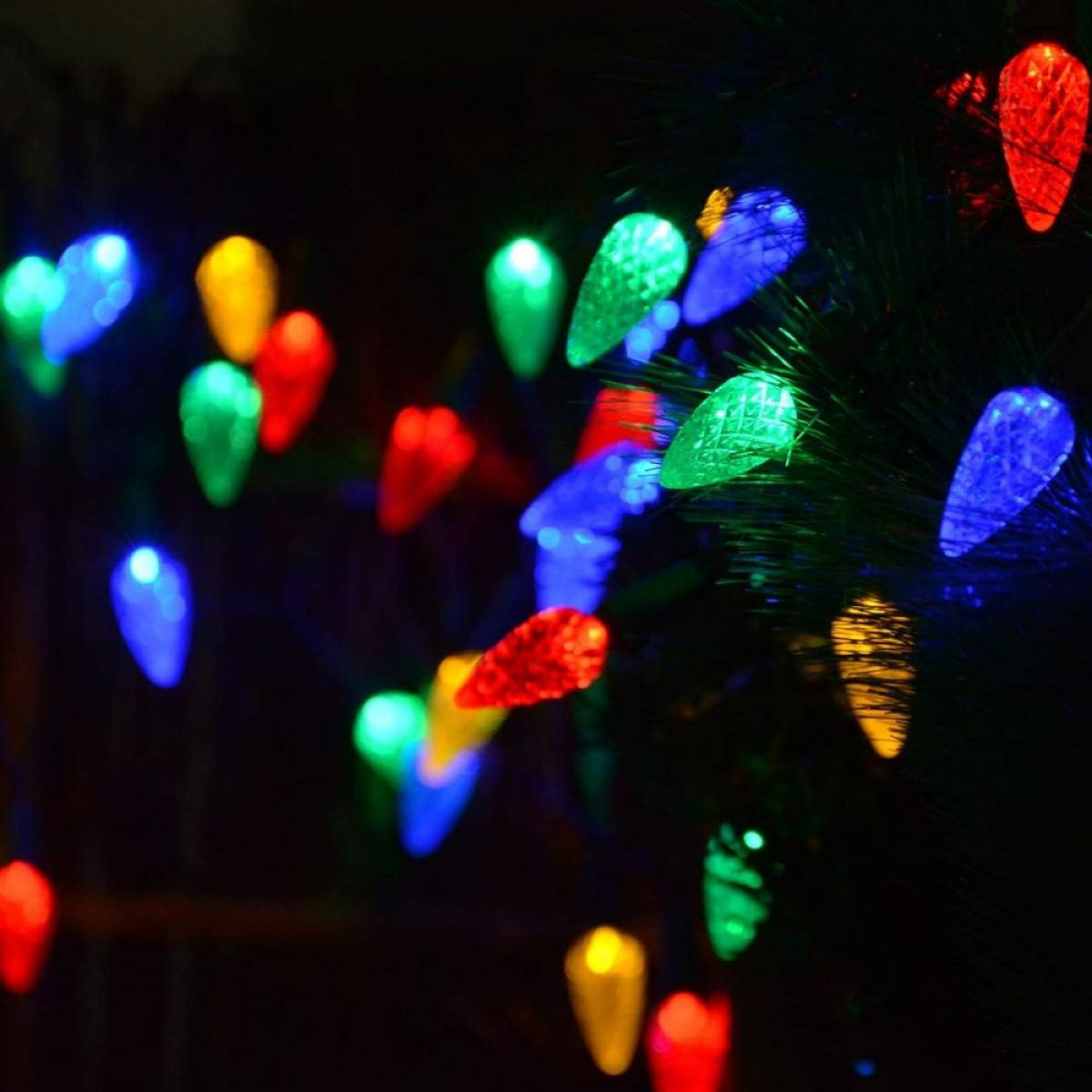 Weihnachtsbeleuchtung. Bunte, kegelförmige Lichter auf dunklem Hintergrund. Rot, grün, blau und gelb.